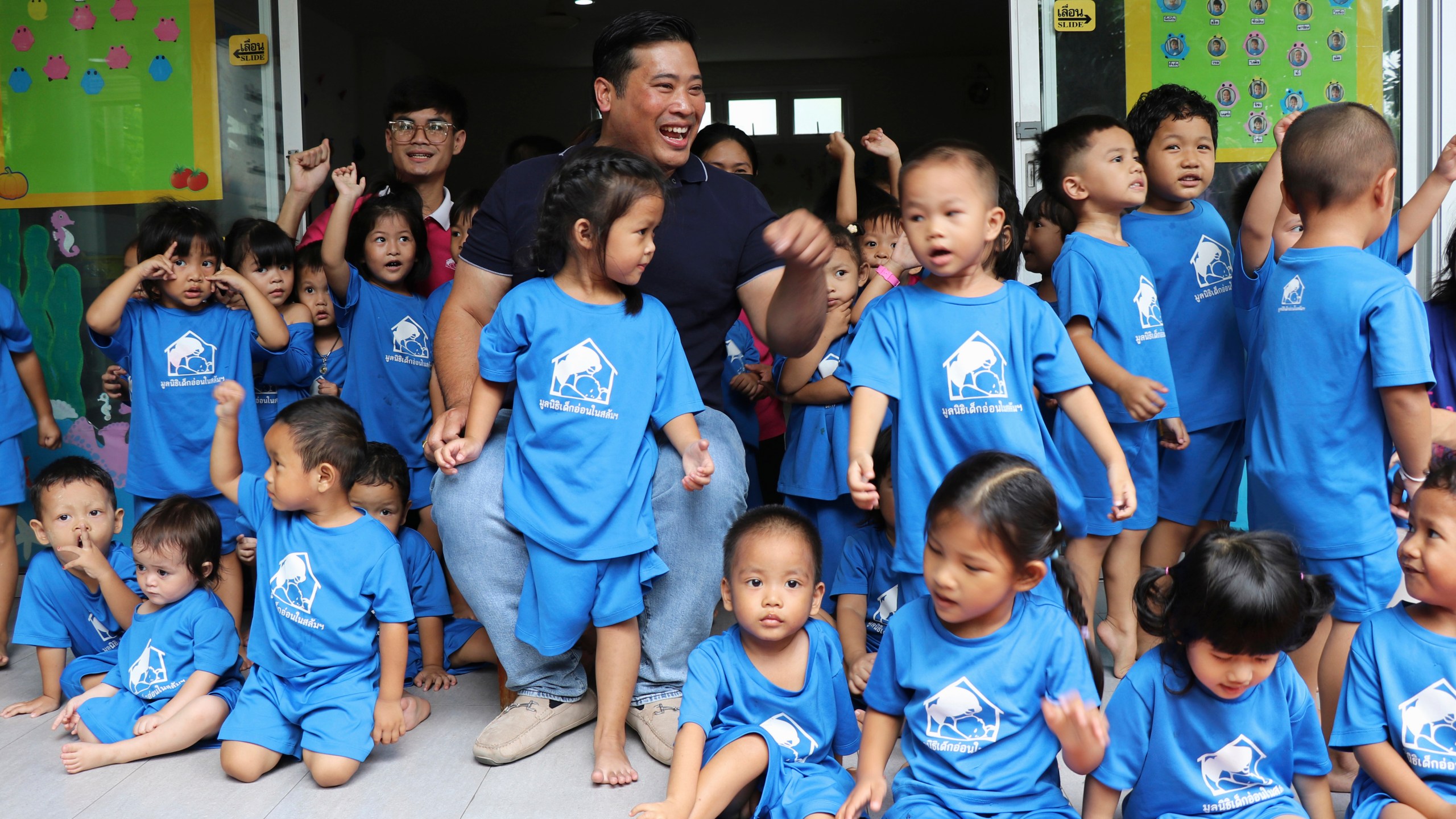 In this photo provided by the Foundation For Slum Child Care, Vacharaesorn Vivacharawongse, center back, visits the daycare center in Bangkok, Thailand, Tuesday, Aug. 8, 2023. The estranged son of Thailand’s King Maha Vajiralongkorn visited the daycare center for underprivileged children in Bangkok on Tuesday following his surprise return to the country after 27 years of living abroad. (Foundation For Slum Child Care via AP)