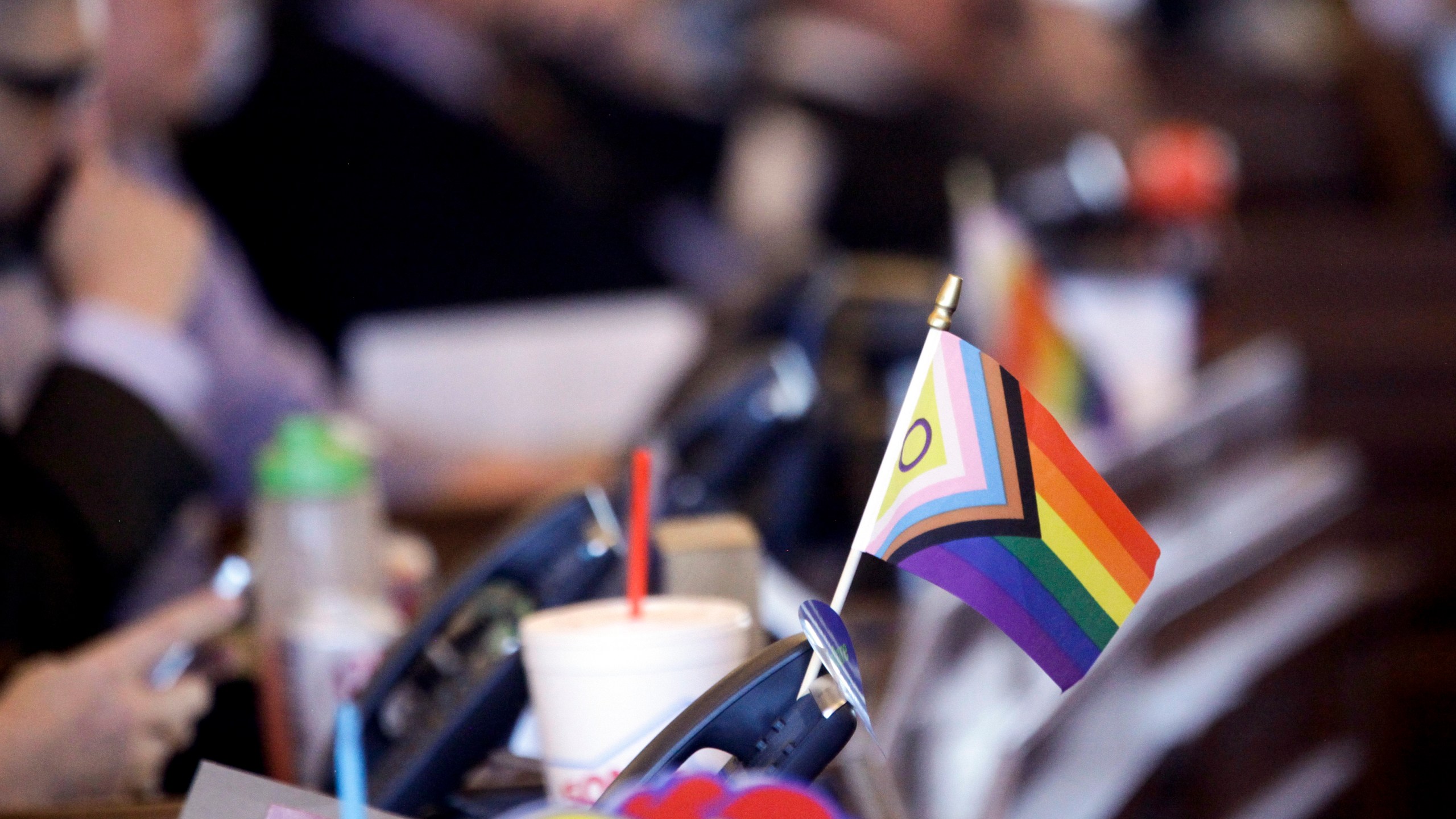 FILE - A flag supporting LGBTQ+ rights decorates a desk on the Democratic side of the Kansas House of Representatives during a debate, March 28, 2023, at the Statehouse in Topeka, Kan. Children are heading back to classes and fall sports practices, and four more states are expecting their K-12 schools to keep transgender girls off their girls sports teams. Kansas, North Dakota and Wyoming had new laws restricting transgender athletes in place before classes resumed, and a Missouri law takes effect at the end of this month. (AP Photo/John Hanna, File)