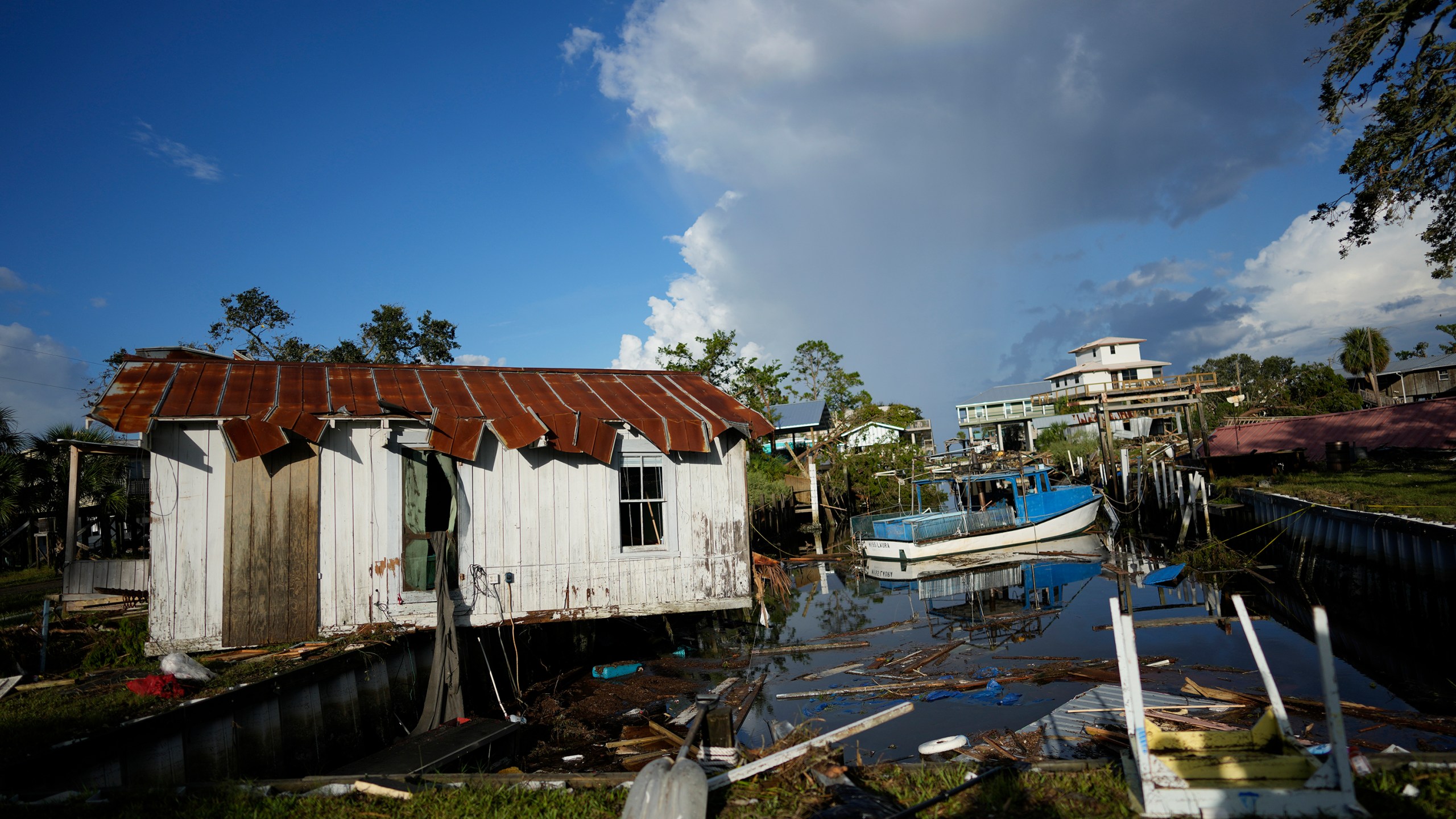 FILE - A cottage belonging to the Ellison family teeters over a canal, alongside the remnants of the family's destroyed business, Ed's Baithouse and Marina, in Horseshoe Beach, Fla., Aug. 31, 2023, one day after the passage of Hurricane Idalia. Americans nationwide face hefty increases in their homeowner’s insurance premiums in the coming years, a report by the First Street Foundation said on Wednesday, Sept. 20, as climate change intensifies floods, wildfires and storms in ways insurance companies are simply unable to keep up with. (AP Photo/Rebecca Blackwell, File)