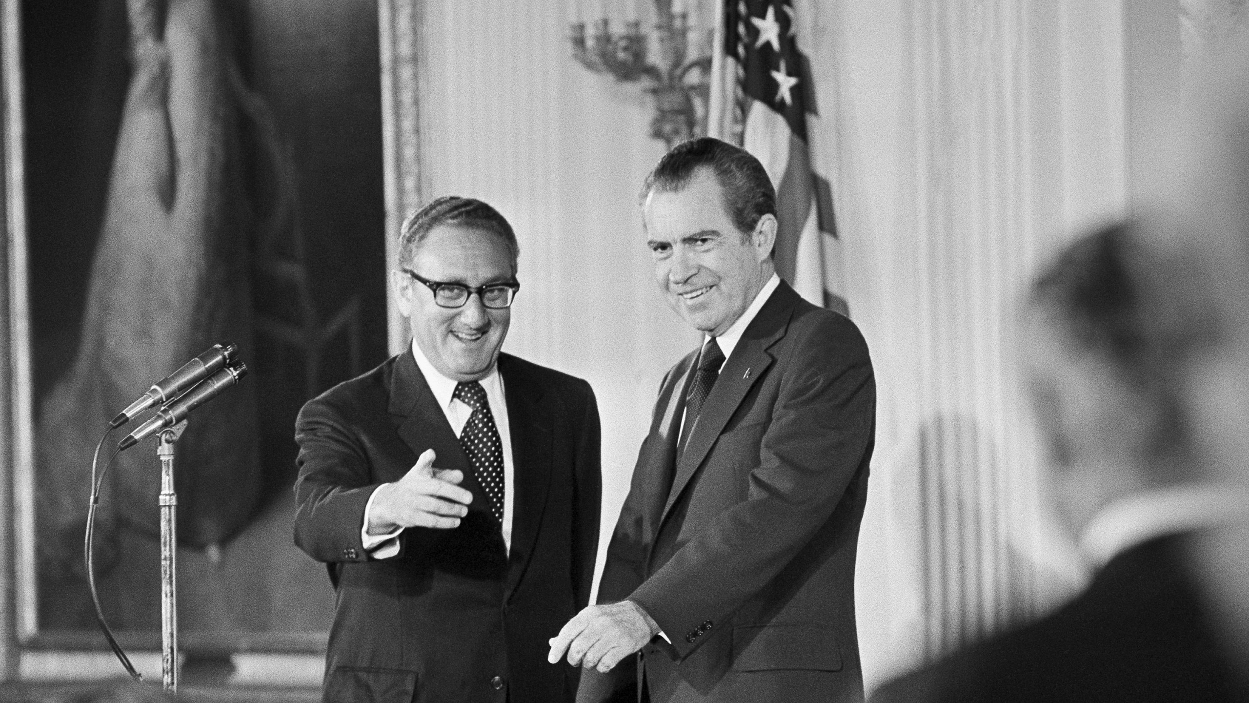 FILE - Secretary of State Henry Kissinger, left, gestures to the audience in the East Room of the White House, Sept. 22, 1973, as President Richard Nixon watches, in Washington. Kissinger had just been sworn in as the 56th secretary of state. Kissinger, the diplomat with the thick glasses and gravelly voice who dominated foreign policy as the United States extricated itself from Vietnam and broke down barriers with China, died Wednesday, Nov. 29, 2023. He was 100. (AP Photo, File)