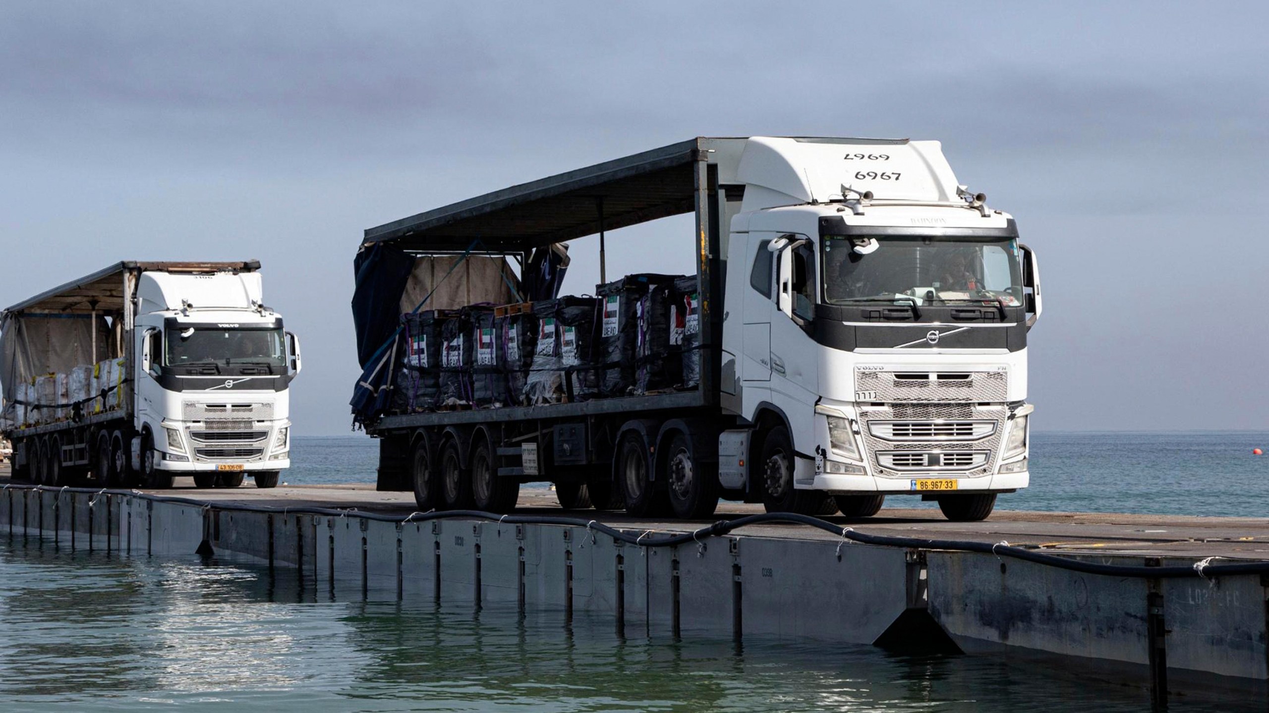 FILE - This image provided by the U.S. Army shows trucks loaded with humanitarian aid from the United Arab Emirates and the United States Agency for International Development cross the Trident Pier before arriving on the beach on the Gaza Strip , May 17, 2024. A U.S. built temporary pier that had been used to deliver additional humanitarian aid into Gaza was damaged by rough seas and has temporarily suspended operations. That’s according to three U.S. officials who spoke to The Associated Press on Tuesday. (Staff Sgt. Malcolm Cohens-Ashley/U.S. Army via AP, File)