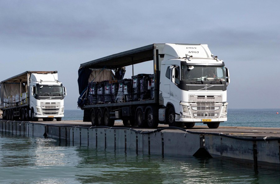 FILE - This image provided by the U.S. Army shows trucks loaded with humanitarian aid from the United Arab Emirates and the United States Agency for International Development cross the Trident Pier before arriving on the beach on the Gaza Strip , May 17, 2024. A U.S. built temporary pier that had been used to deliver additional humanitarian aid into Gaza was damaged by rough seas and has temporarily suspended operations. That’s according to three U.S. officials who spoke to The Associated Press on Tuesday. (Staff Sgt. Malcolm Cohens-Ashley/U.S. Army via AP, File)