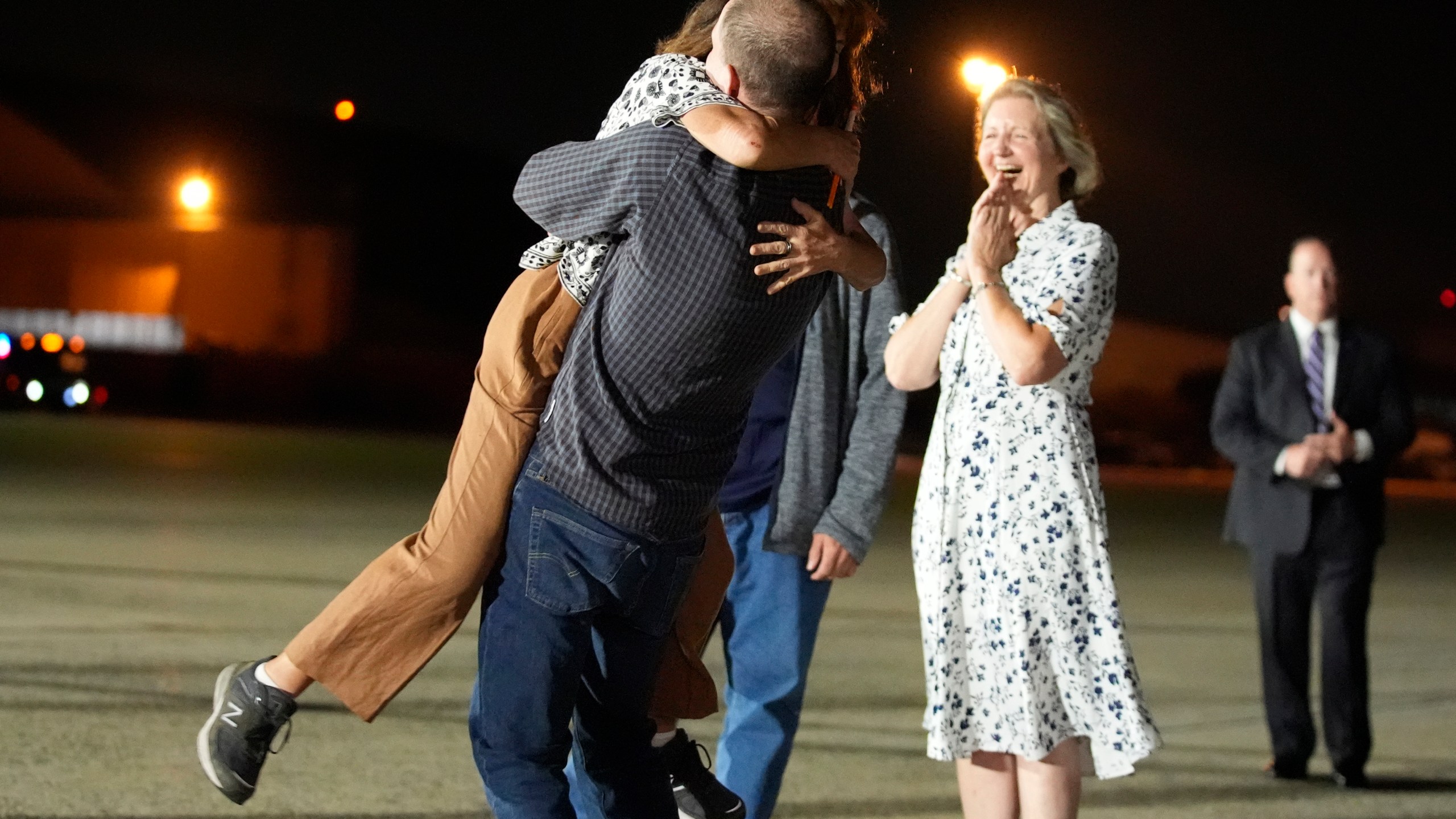 FILE - Reporter Evan Gershkovich hugs his mother Ella Milman, left, at Andrews Air Force Base, Md., following his release as part of a 24-person prisoner swap between Russia and the United States, Aug. 1, 2024. Looking on at right is Elizabeth Whelan, sister of released prisoner Paul Whelan. Bloomberg News is apologizing for a premature story written about the prisoner exchange and says it has disciplined the journalists involved. The story was put out by Bloomberg hours before an embargo was lifted by the White House. (AP Photo/Alex Brandon, File)