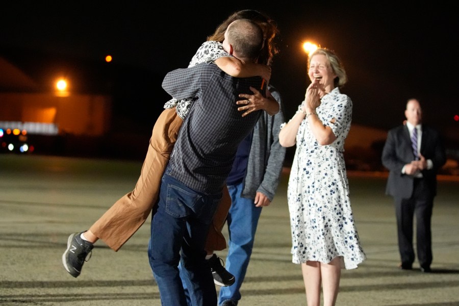 FILE - Reporter Evan Gershkovich hugs his mother Ella Milman, left, at Andrews Air Force Base, Md., following his release as part of a 24-person prisoner swap between Russia and the United States, Aug. 1, 2024. Looking on at right is Elizabeth Whelan, sister of released prisoner Paul Whelan. Bloomberg News is apologizing for a premature story written about the prisoner exchange and says it has disciplined the journalists involved. The story was put out by Bloomberg hours before an embargo was lifted by the White House. (AP Photo/Alex Brandon, File)