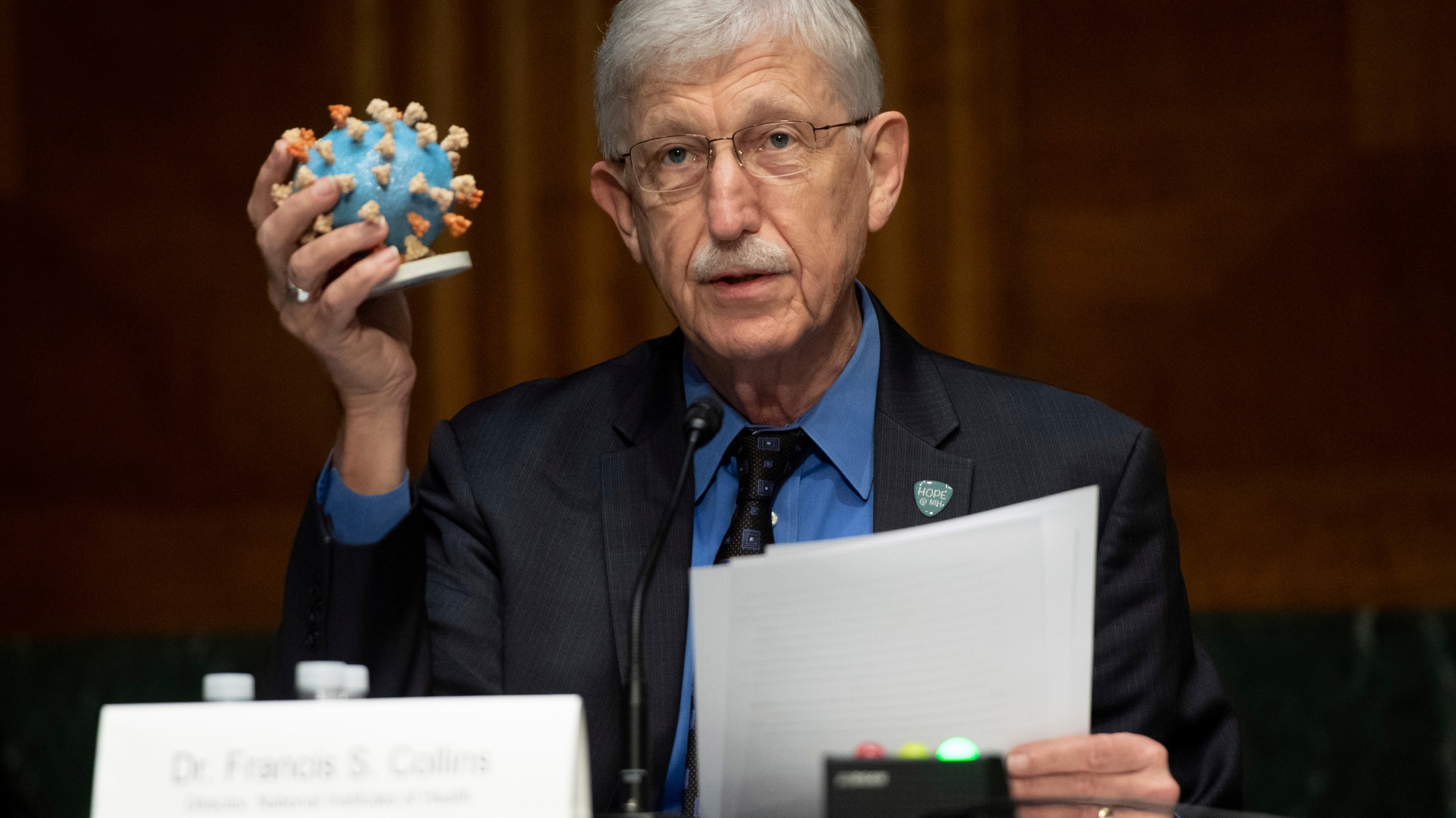 FILE- Dr. Francis Collins, Director of the National Institutes of Health (NIH), holds up a model of COVID-19, known as coronavirus, during a Senate Appropriations subcommittee hearing on the plan to research, manufacture and distribute a coronavirus vaccine, known as Operation Warp Speed, Thursday, July 2, 2020, on Capitol Hill in Washington. (Saul Loeb/Pool Photo via AP, File)