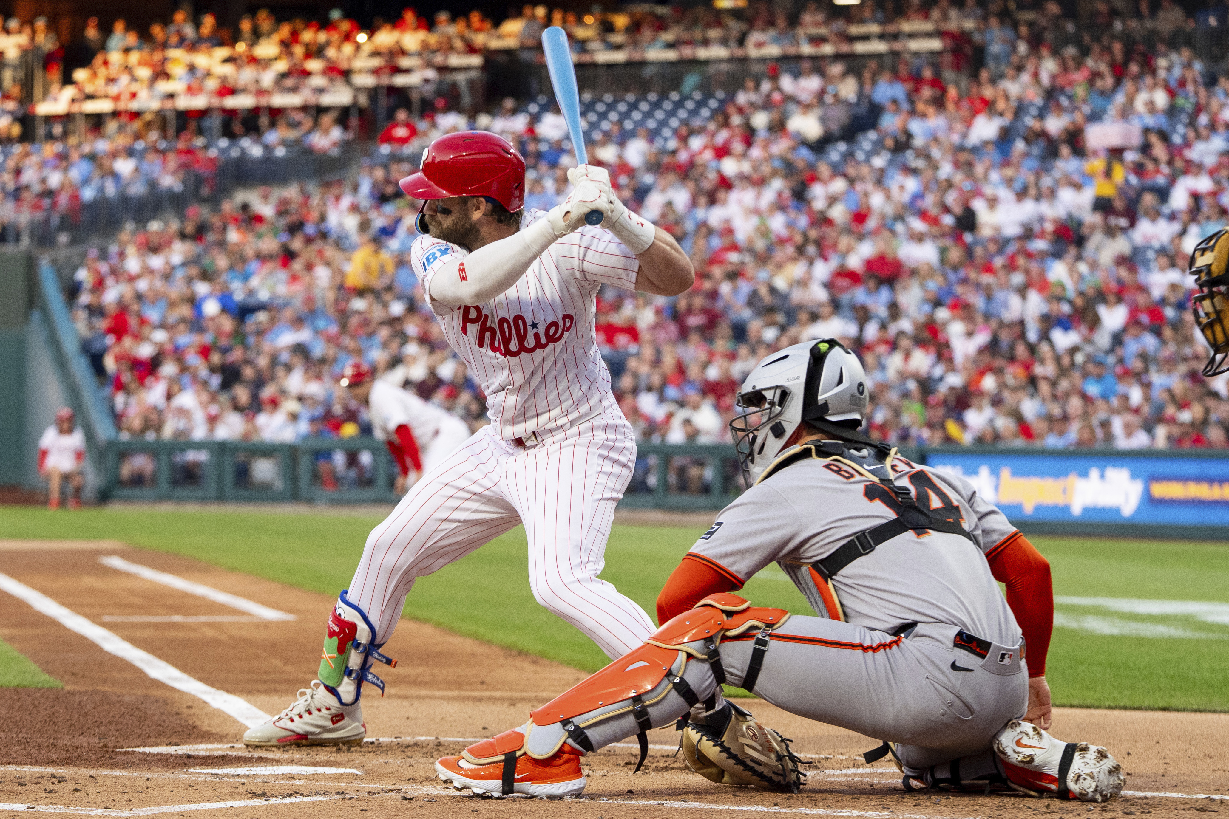 Philadelphia Phillies' Bryce Harper, left, takes an at-bat during the first inning of a baseball game against the San Francisco Giants, Monday, April 14, 2025, in Philadelphia. (AP Photo/Chris Szagola)