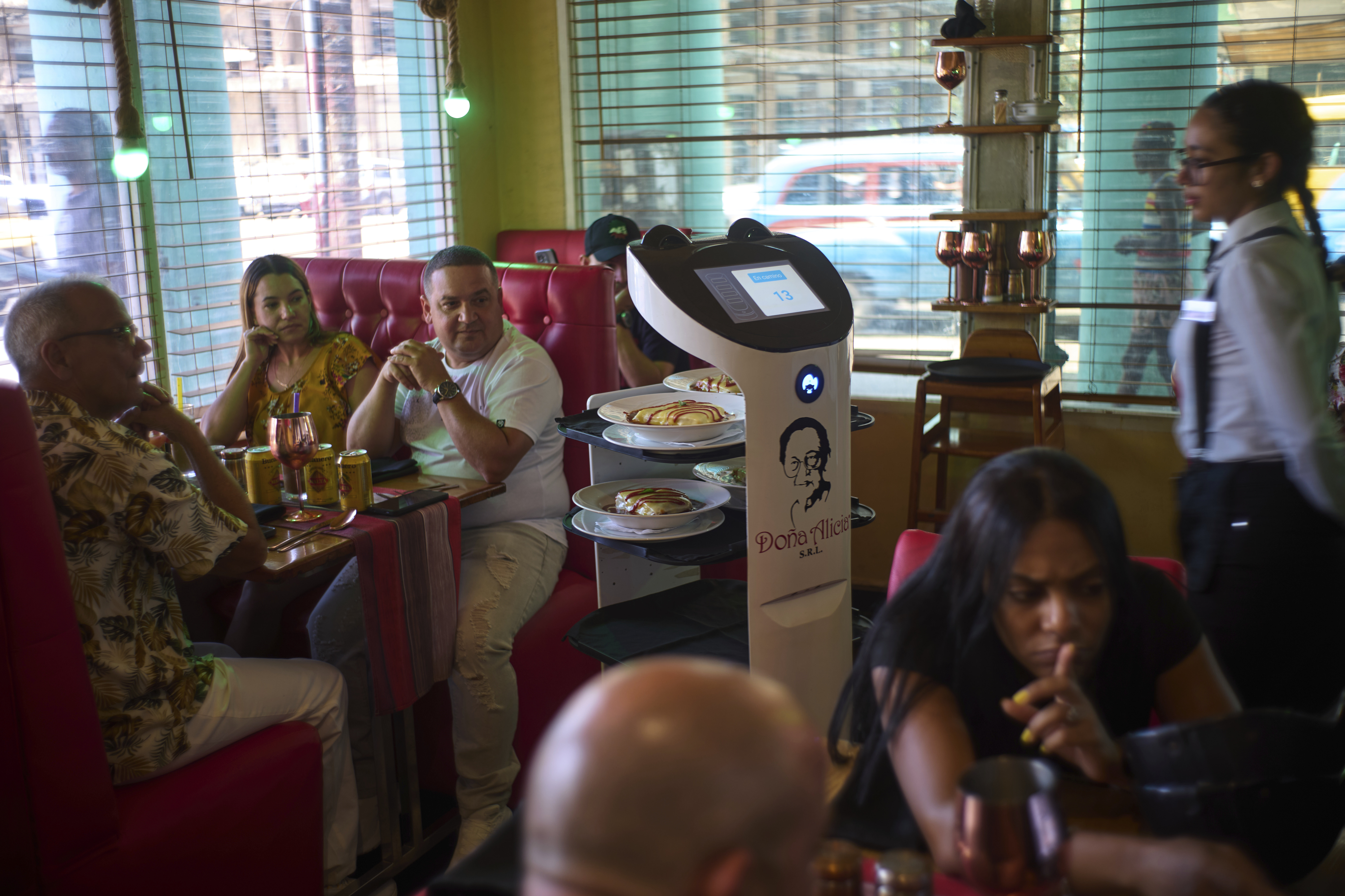 Customers watch as a robot arrives with their food at Dona Alicia restaurant in Havana, Wednesday, April 15, 2025. (AP Photo/Ramon Espinosa)