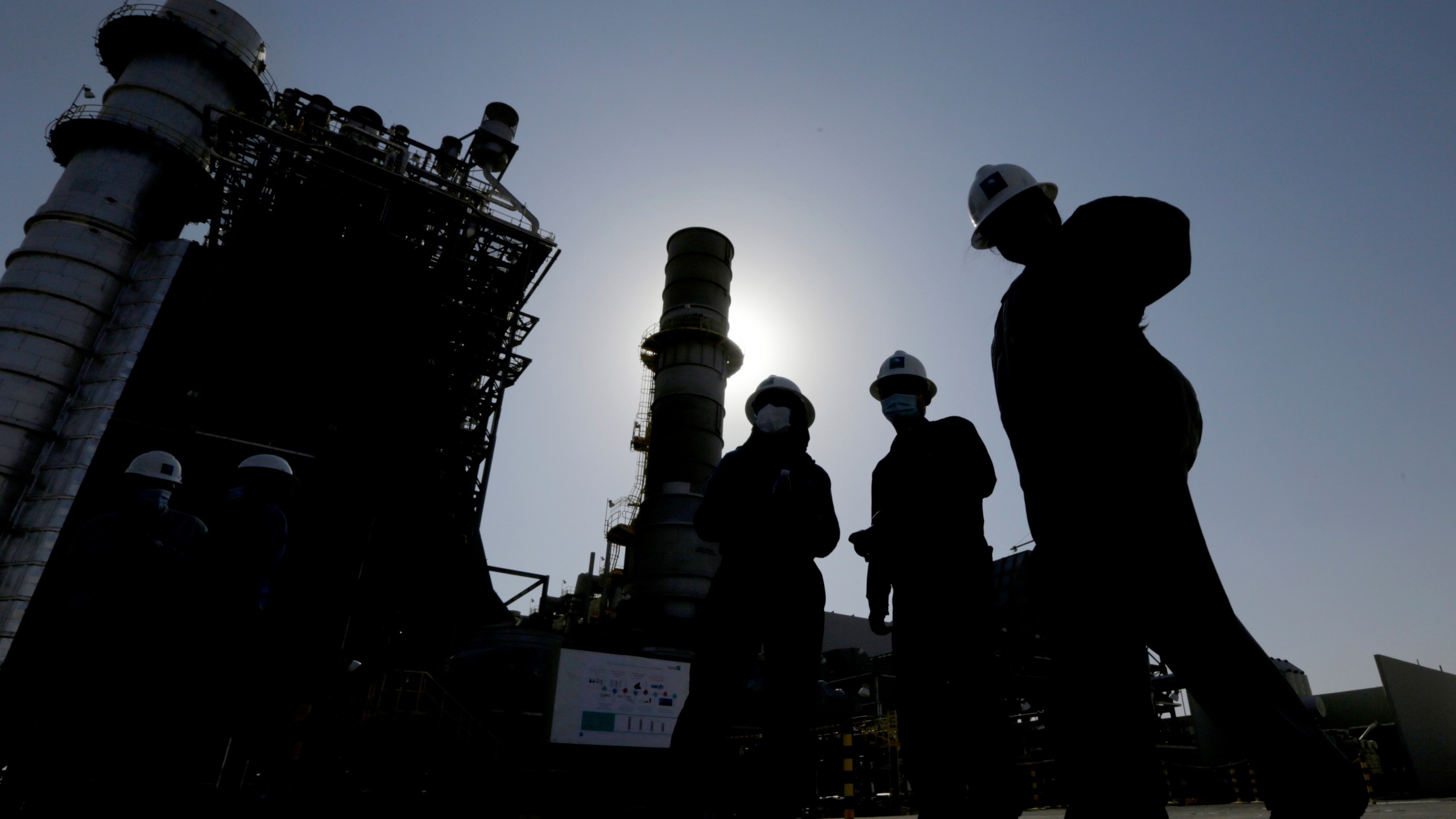 FILE - Saudi Aramco engineers walk in front of a gas turbine generator at Khurais oil field during a tour for journalists, outside of Riyadh, Saudi Arabia on June 28, 2021. (AP Photo/Amr Nabil, File)