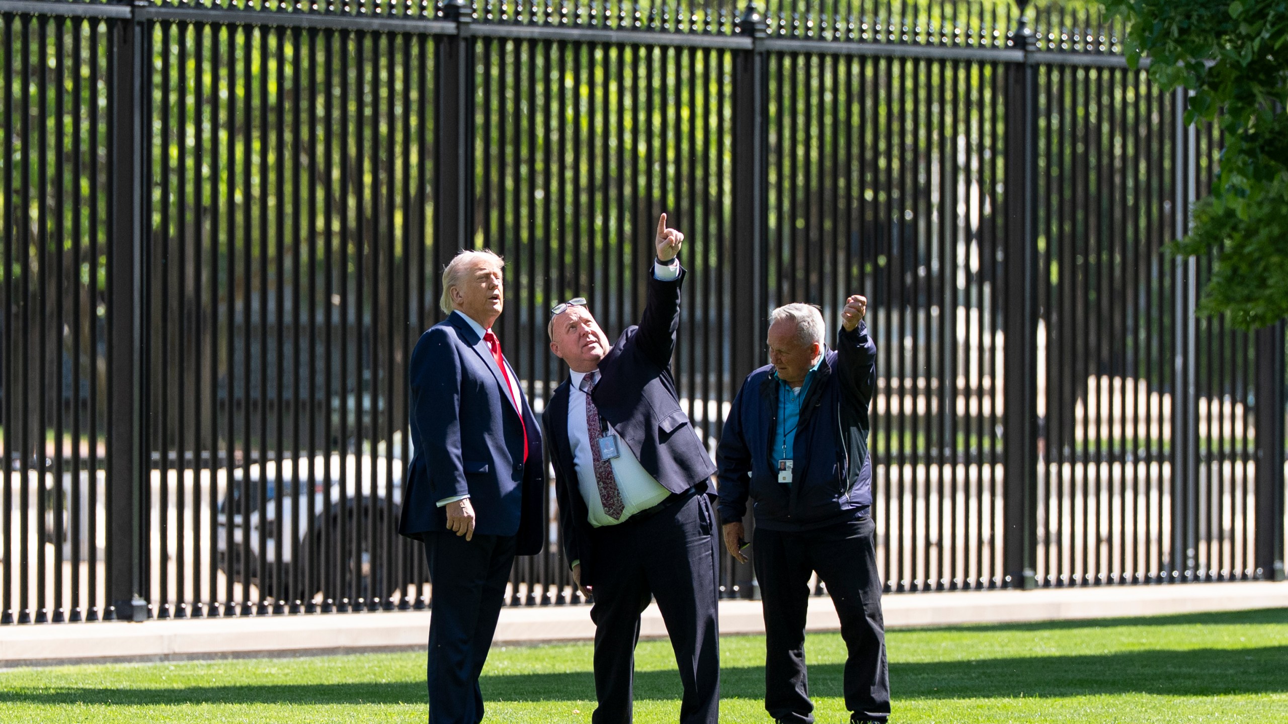 President Donald Trump, left, speaks with Dale Haney, head White House grounds keeper, right, and others, about a new flagpole on the North Lawn of the White House, Wednesday, April 23, 2025, in Washington. (AP Photo/Alex Brandon)