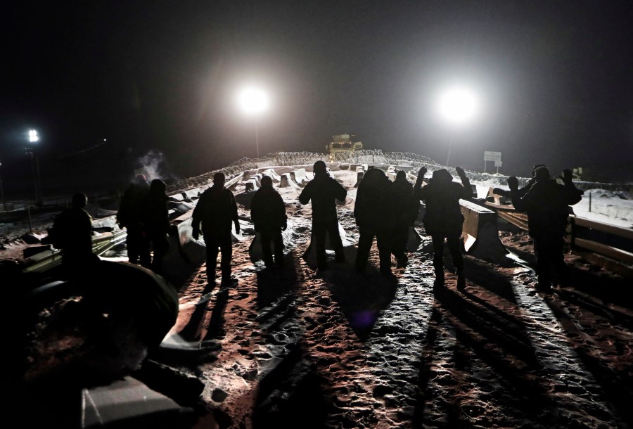FILE - Military veterans walk onto a closed bridge to protest across from police protecting the Dakota Access oil pipeline site in Cannon Ball, N.D., Thursday, Dec. 1, 2016. (AP Photo/David Goldman, File)