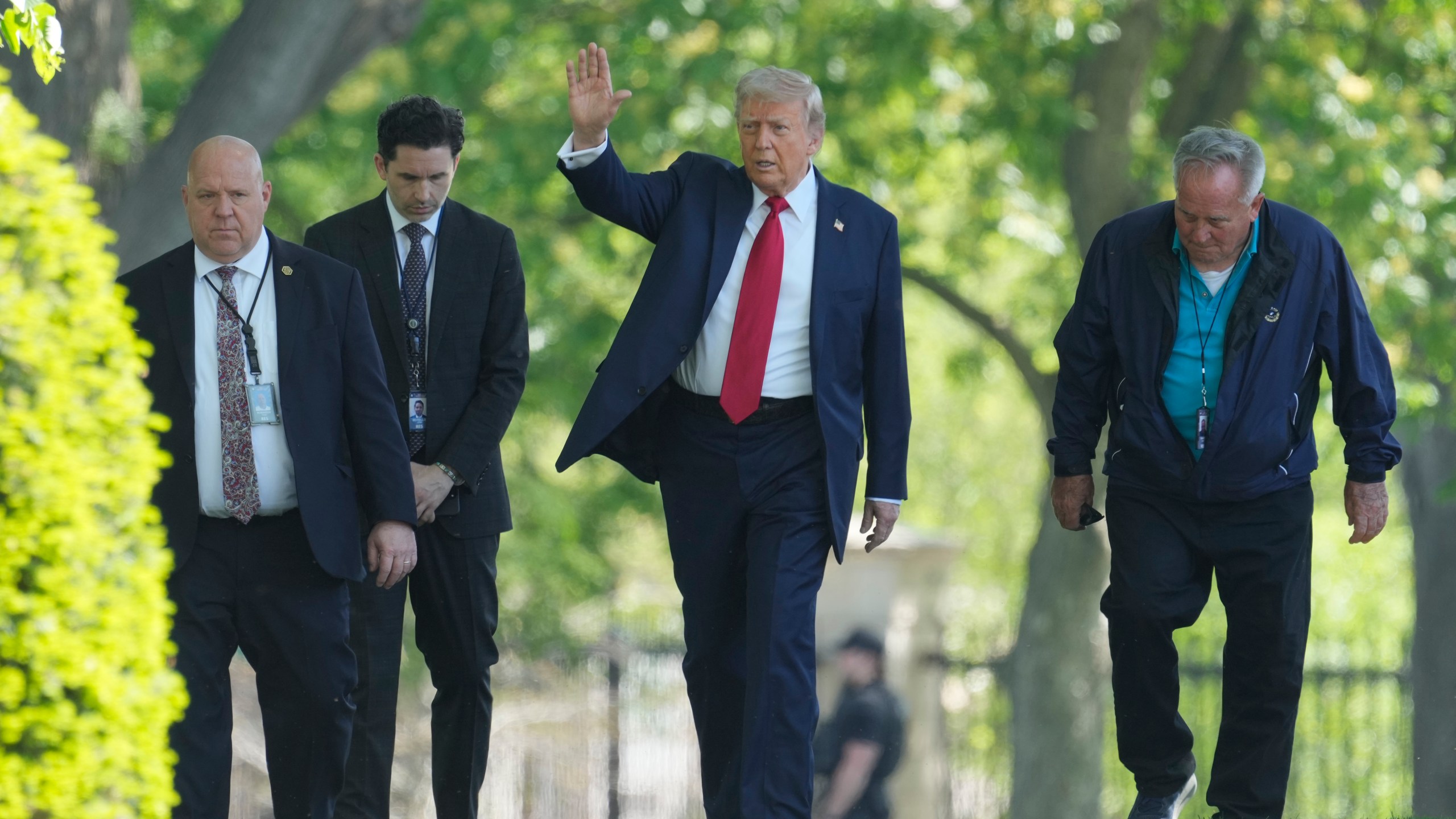 President Donald Trump, center, waving as he walks with staff members on the North Lawn of the White House in Washington, Wednesday, April 23, 2025. (AP Photo/Mark Schiefelbein)