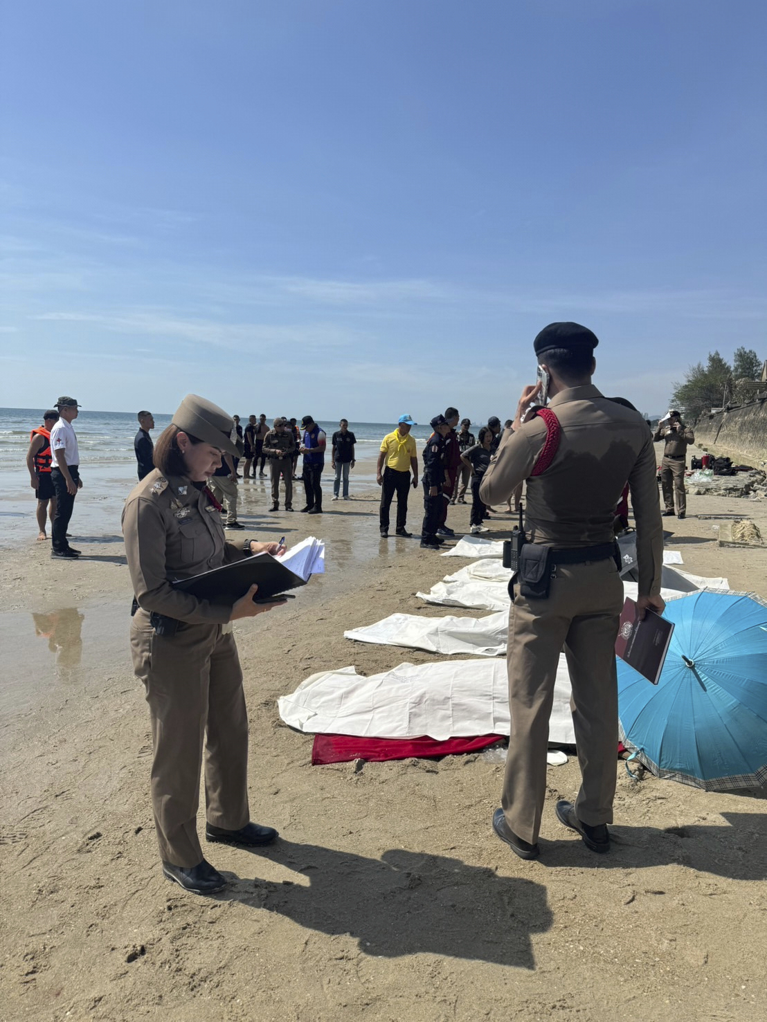 In this photo provided by the Royal Thai Police, police officers investigate the scene after a small police plane crashed into the sea, killing multiple people on board, in Prachuab Kiri Khan province, western of Thailand, Friday, April 25, 2025. (Royal Thai Police via AP)