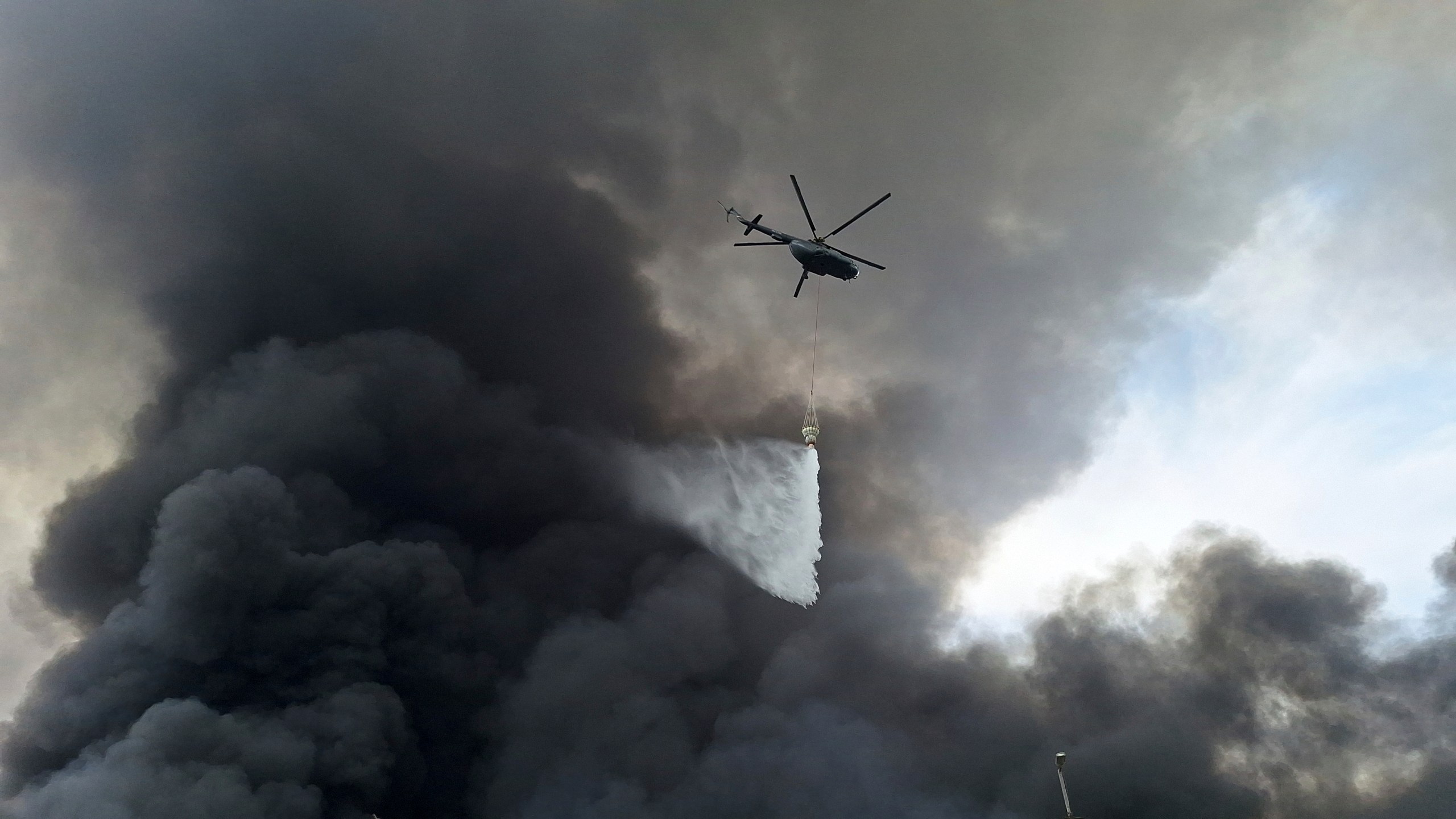 A helicopter drops water on the fire, Sunday, April 27, 2025, after a massive explosion and fire rocked a port near the southern port city of Bandar Abbas, Iran on Saturday. (AP Photo/Meysam Mirzadeh/Tasnim News)