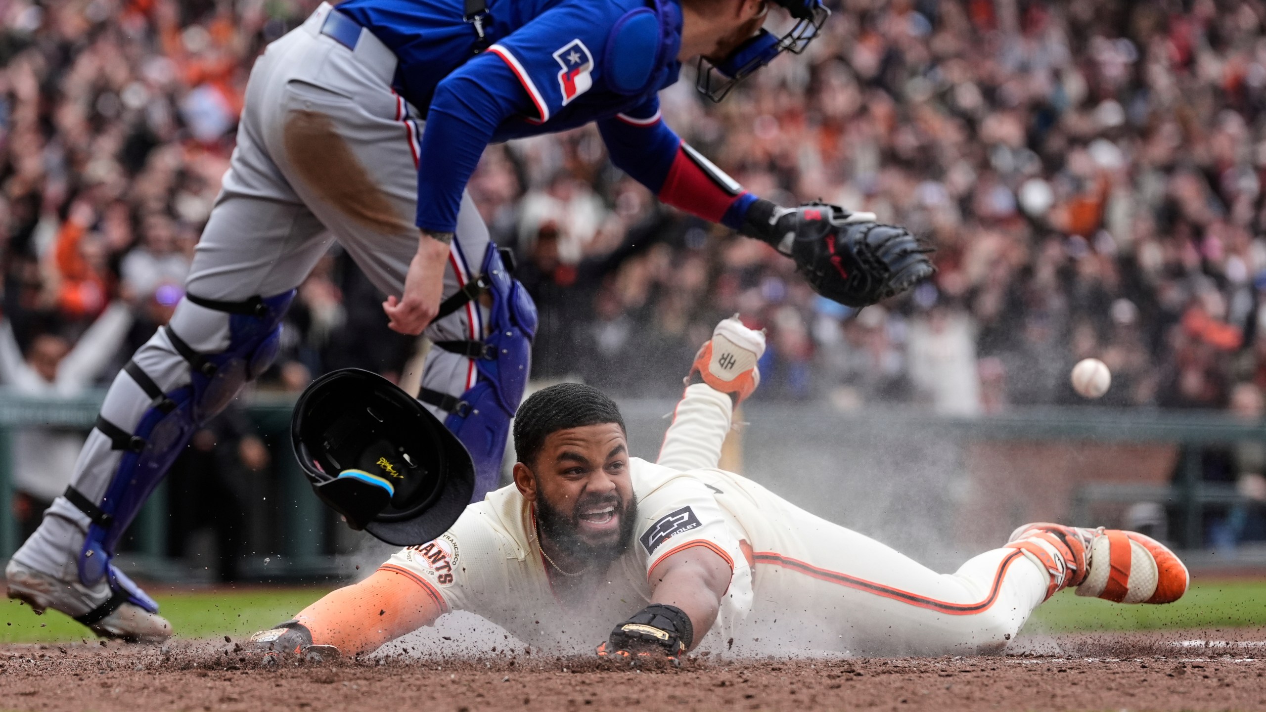 San Francisco Giants' Heliot Ramos scores the game-winning run on a throwing error Texas Rangers first baseman Jake Burger during the ninth inning of a baseball game Sunday, April 27, 2025, in San Francisco. (AP Photo/Godofredo A. Vásquez)