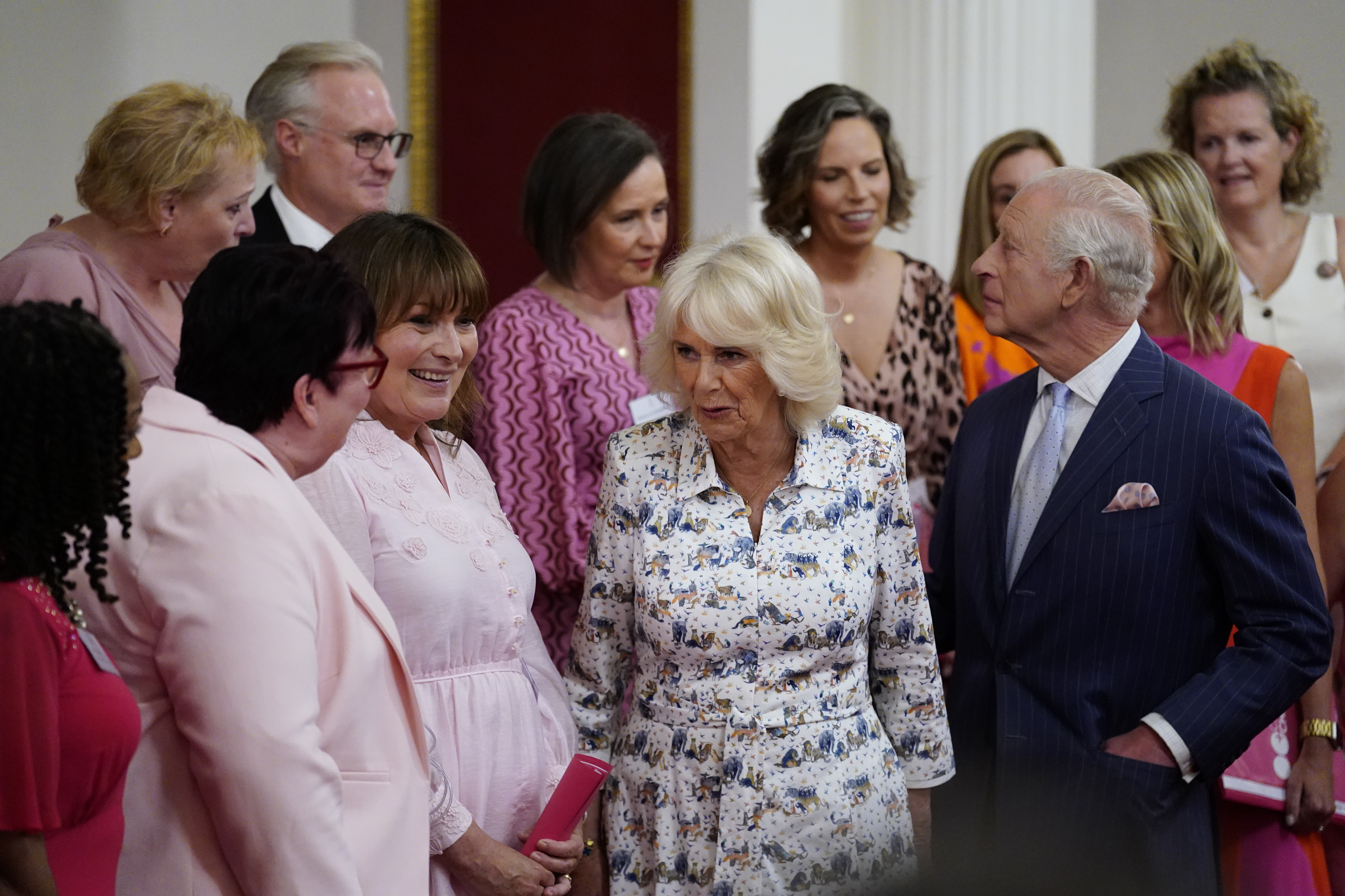 Britain's King Charles III and Queen Camilla speak with presenter Lorraine Kelly, second left, and the members of the Change + Check Choir, during a reception in Buckingham Palace, London, in celebration of community-based initiatives raising awareness about cancer and supporting those living with cancer, Wednesday April 30, 2025. (Andrew Matthews/Pool Photo via AP)