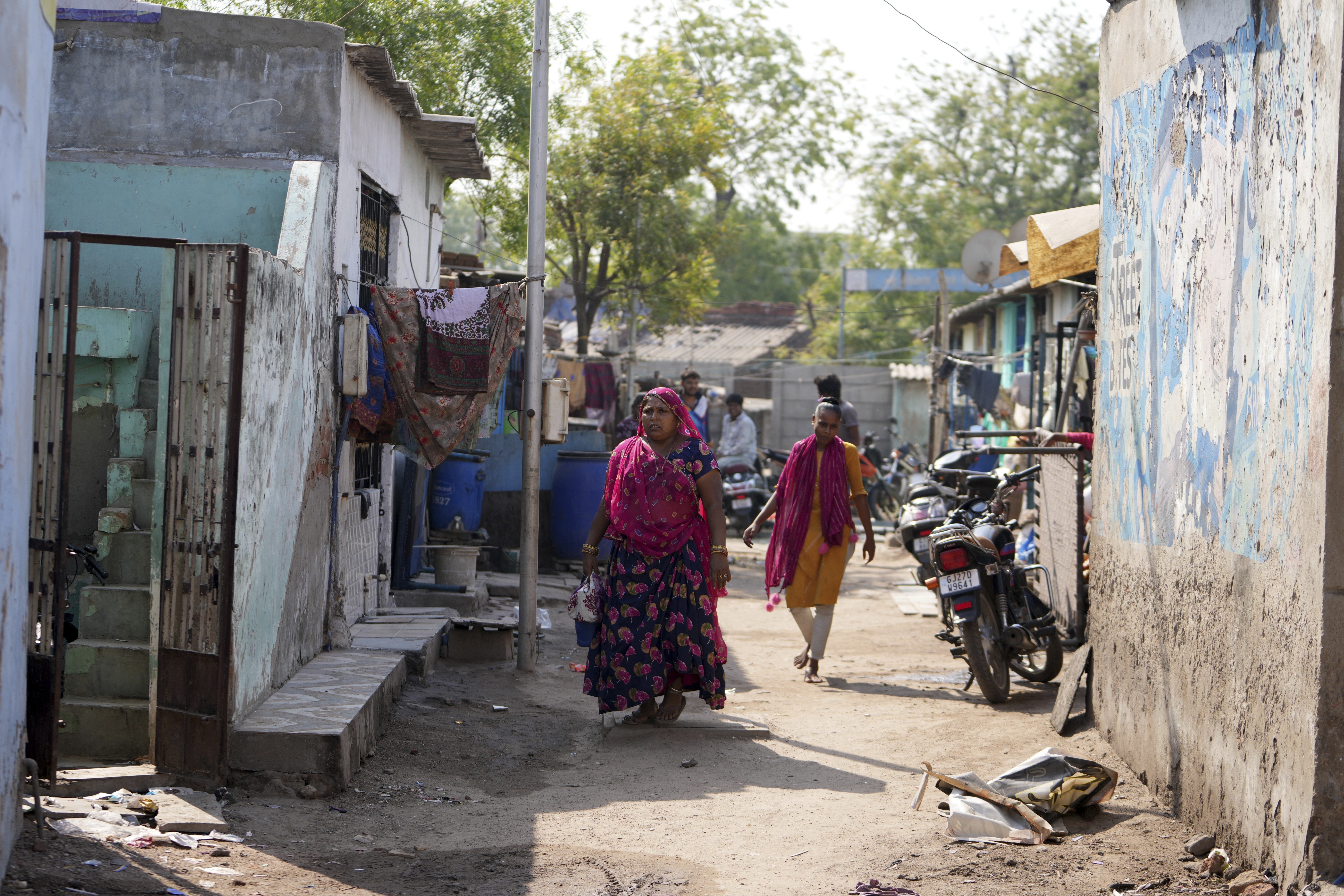 People walk through buildings in Vanzara Vas, a low-income neighborhood, in Ahmedabad, India, Wednesday, April 2, 2025. (AP Photo/Ajit Solanki)
