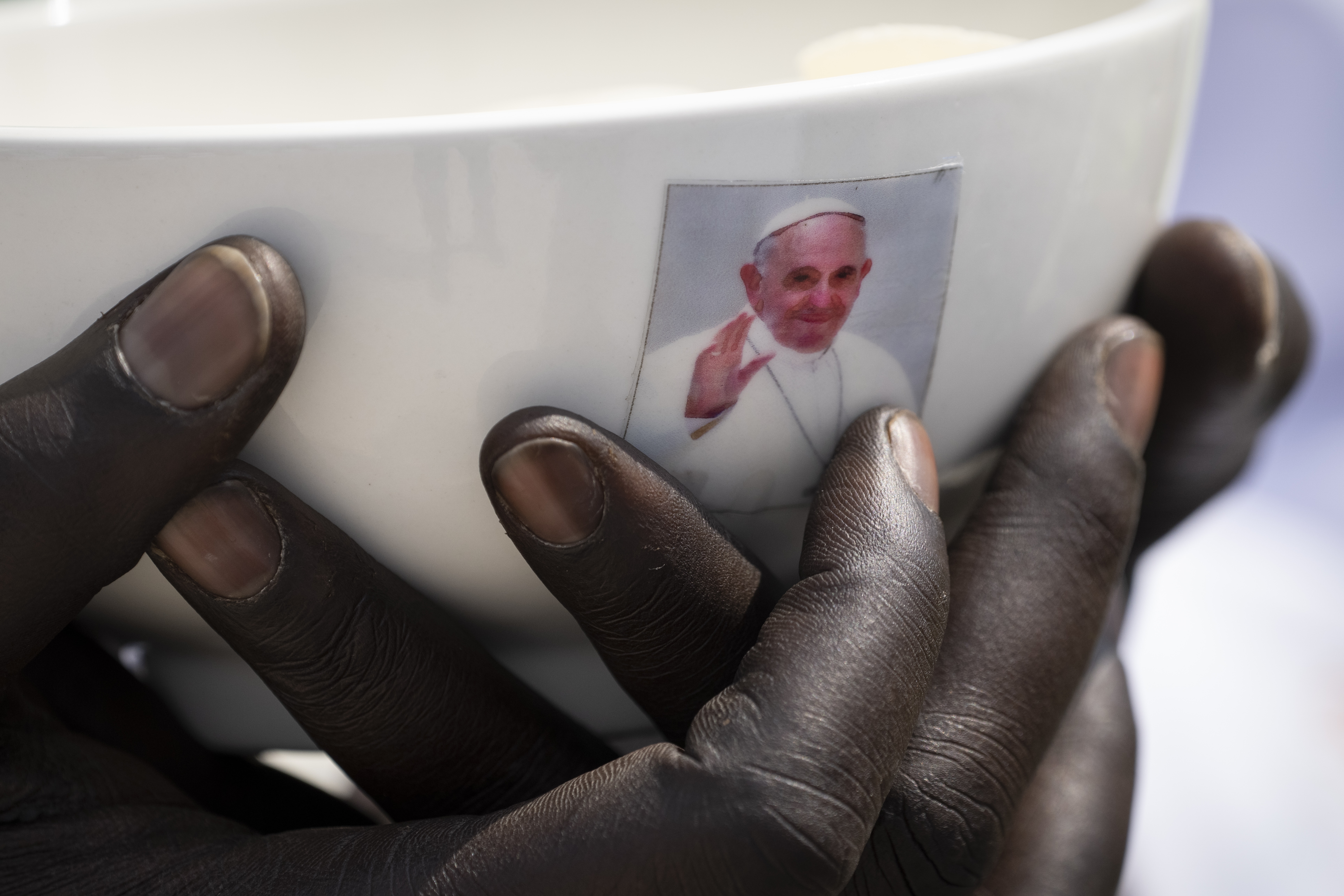 FILE - A priest holds a sacrament bowl showing a photograph of Pope Francis during a Holy Mass at the John Garang Mausoleum in Juba, South Sudan, Feb. 5, 2023. (AP Photo/Ben Curtis, File)
