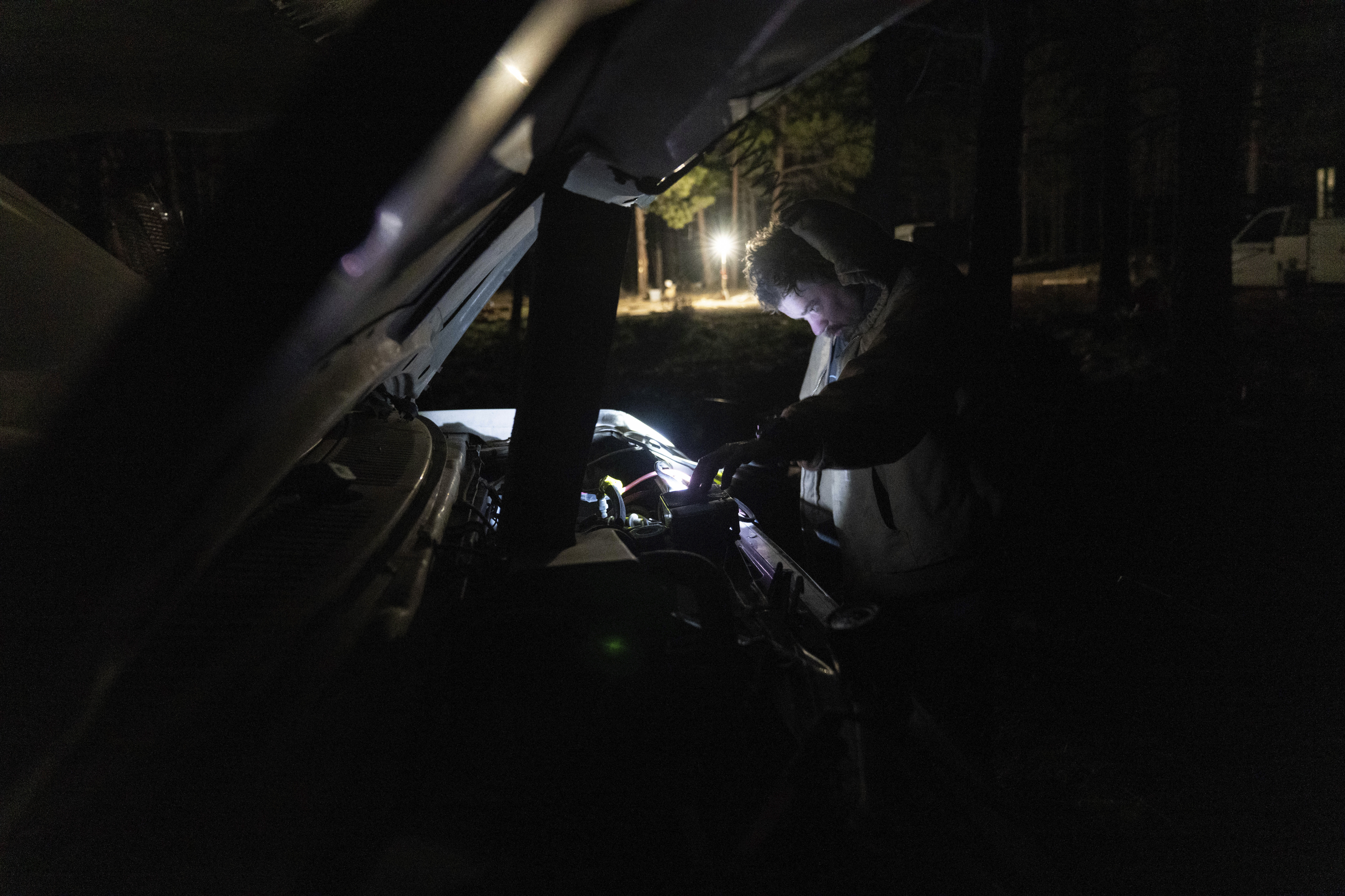 Greg Bishop works to get an RV to start at a homeless encampment in Deschutes National Forest Wednesday, April 30, 2025 near Bend, Ore. (AP Photo/Jenny Kane)