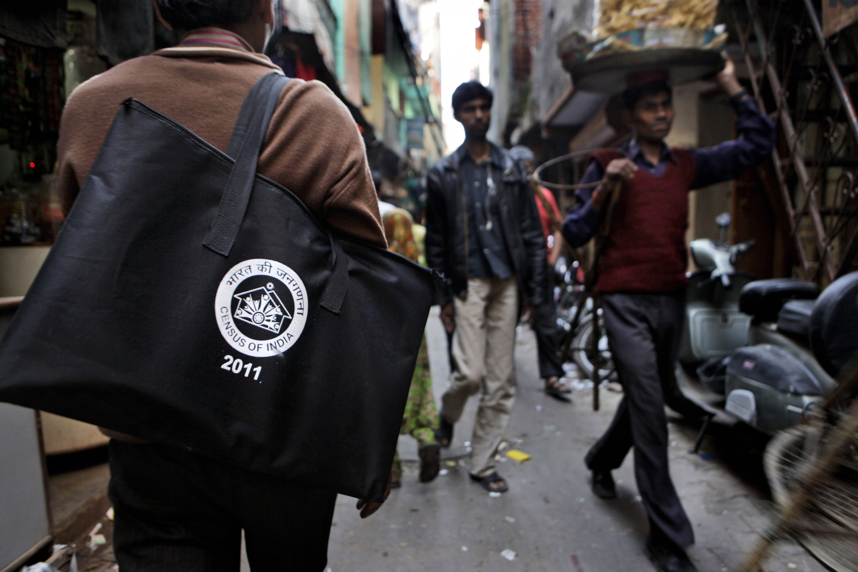 FILE -An Indian government census enumerator Pawan Kumar, left, walks down a street in New Delhi, India, Feb. 10, 2011. (AP Photo/Manish Swarup, File)