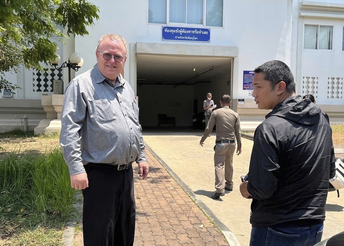 FILE - U.S. political science lecturer Paul Chambers, left, of Thailand's Naresuan University, stands outside the police station in Phitsanulok, Thailand, where he was arrested on charges of insulting the monarchy. (AP Photo, file)