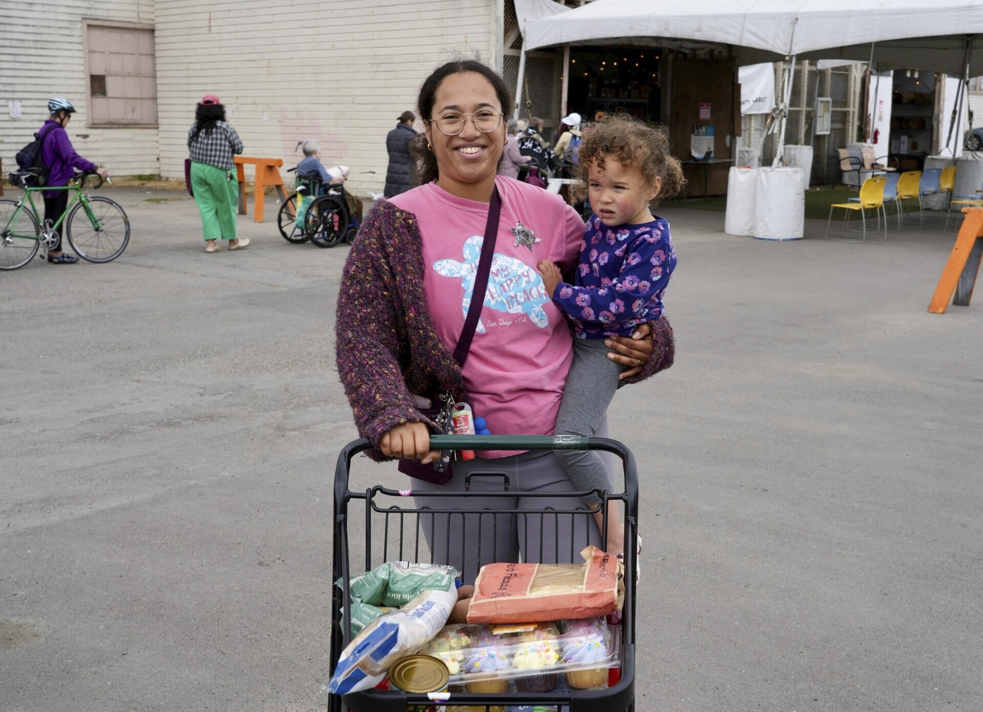 Alameda resident Christina Santamaria stands outside the Alameda Food Bank with groceries and her daughter in Alameda, Calif. on Friday, April 25, 2025. (AP Photo/Terry Chea)
