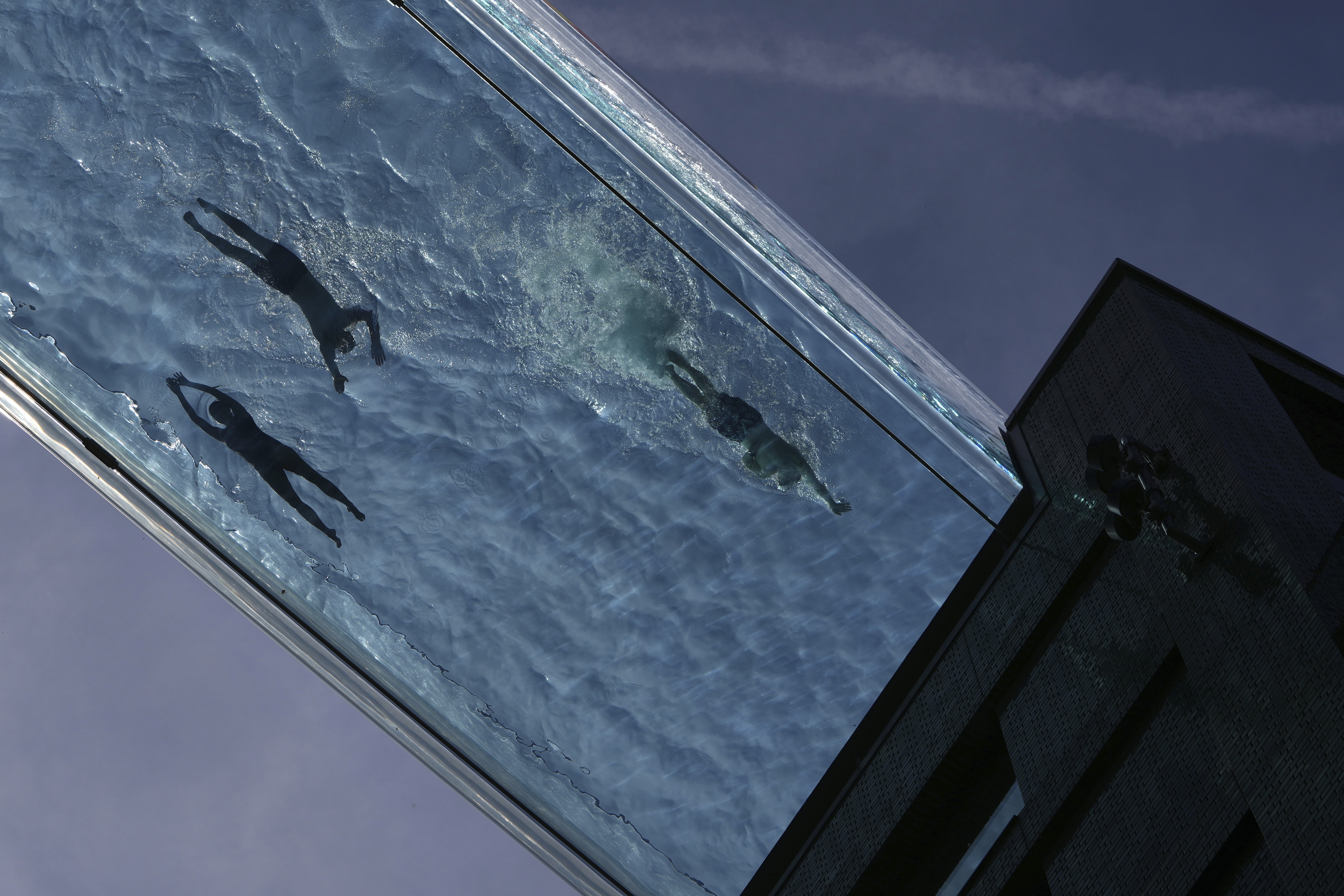People swim in the Sky Pool on a sunny day in London, Thursday, May 1, 2025. (AP Photo/Kin Cheung)