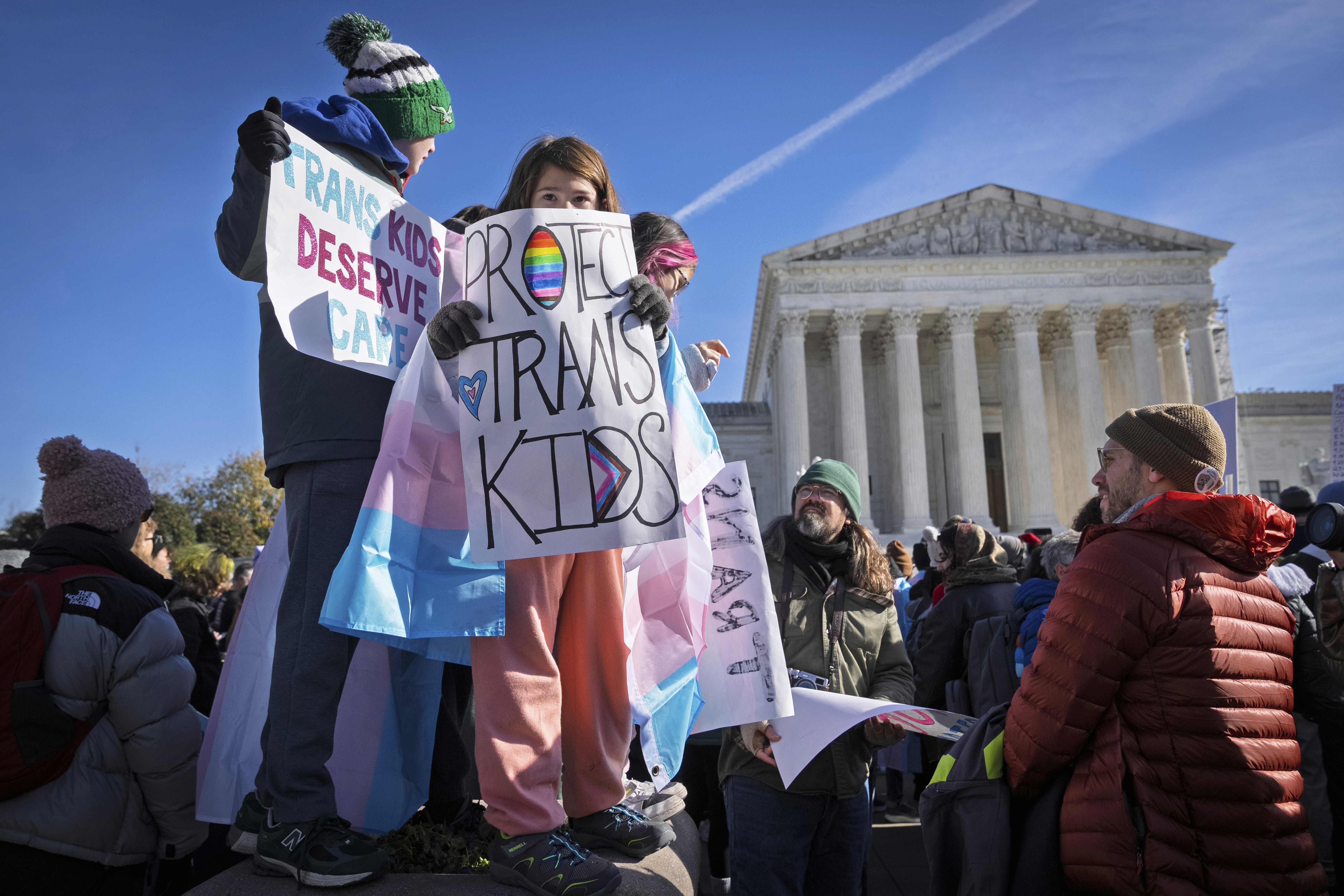 FILE - Children hold signs and transgender pride flags as supporters of transgender rights rally by the Supreme Court, Dec. 4, 2024, in Washington. (AP Photo/Jacquelyn Martin, File)