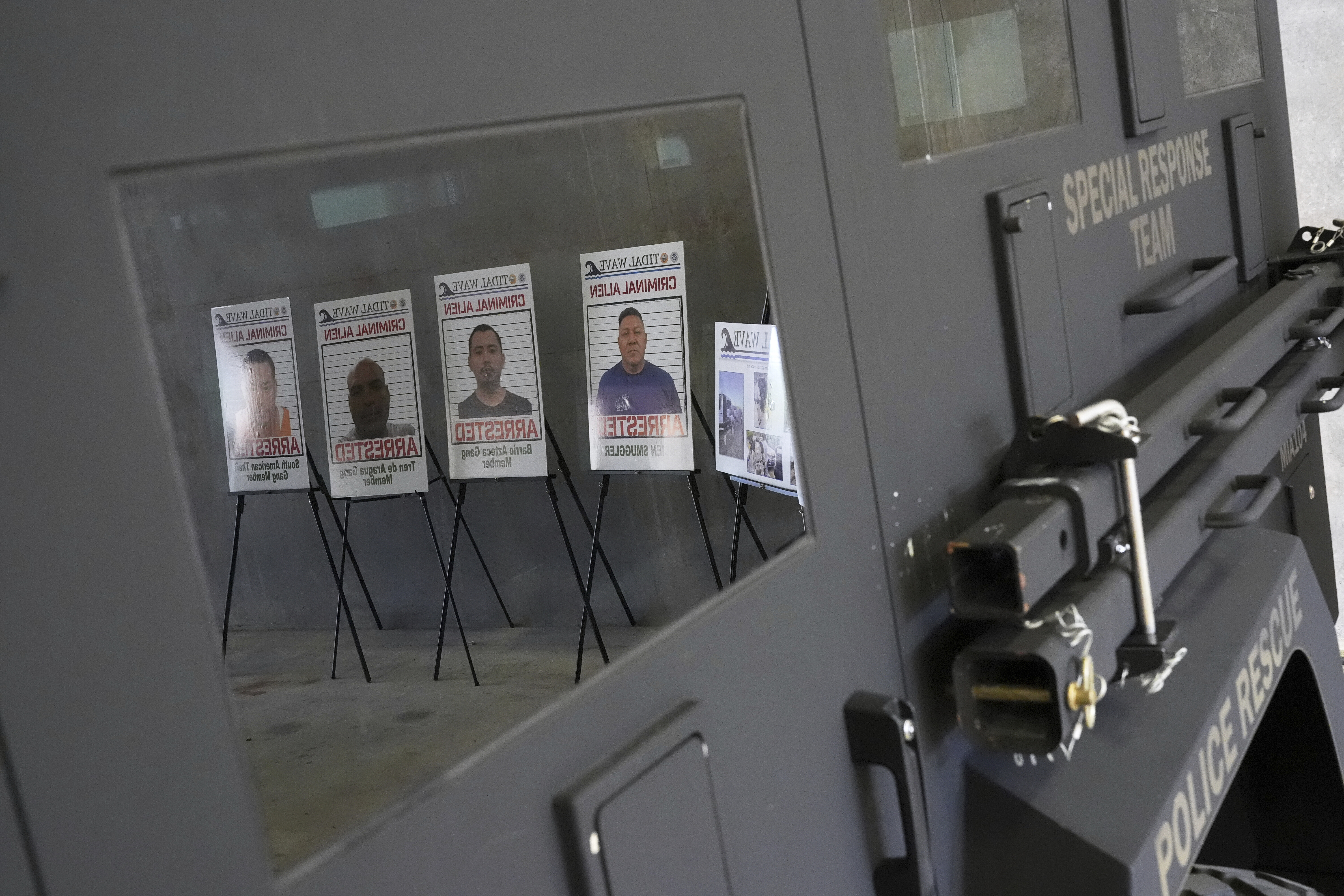 Posters of alleged criminals who officials said were arrested in a recent immigration enforcement operation are reflected in a Department of Homeland Security vehicle during a press conference with Gov. Ron DeSantis at the South Florida office of U.S. Immigration and Customs Enforcement and Enforcement and Removal Operations, Thursday, May 1, 2025, in Miramar, Fla. (AP Photo/Rebecca Blackwell)