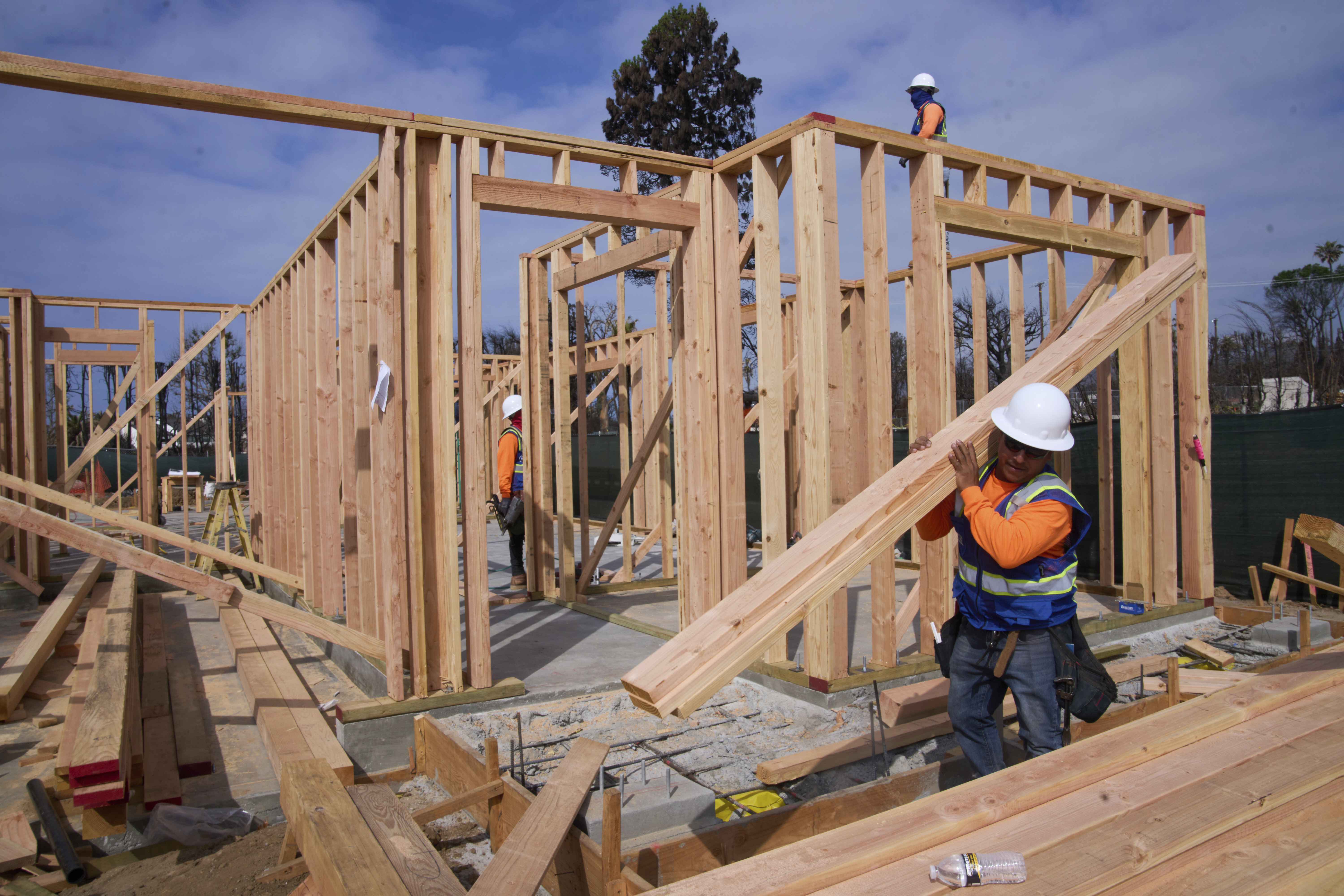 Workers rebuild a property destroyed by the Palisades Fire in the Pacific Palisades neighborhood of Los Angeles, Thursday, April 24, 2025. (AP Photo/Damian Dovarganes)