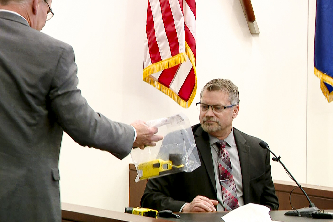 Kent County Prosecutor Chris Becker shows Bryan Chiles, senior manager of Axon Forensics, the Taser7 used by former Grand Rapids Police officer Christopher Schurr on Patrick Lyoya during the second day of trial at the Kent County Courthouse in Grand Rapids, Mich. on Tuesday, April 29, 2025. (WOOD-TV via AP, Pool)