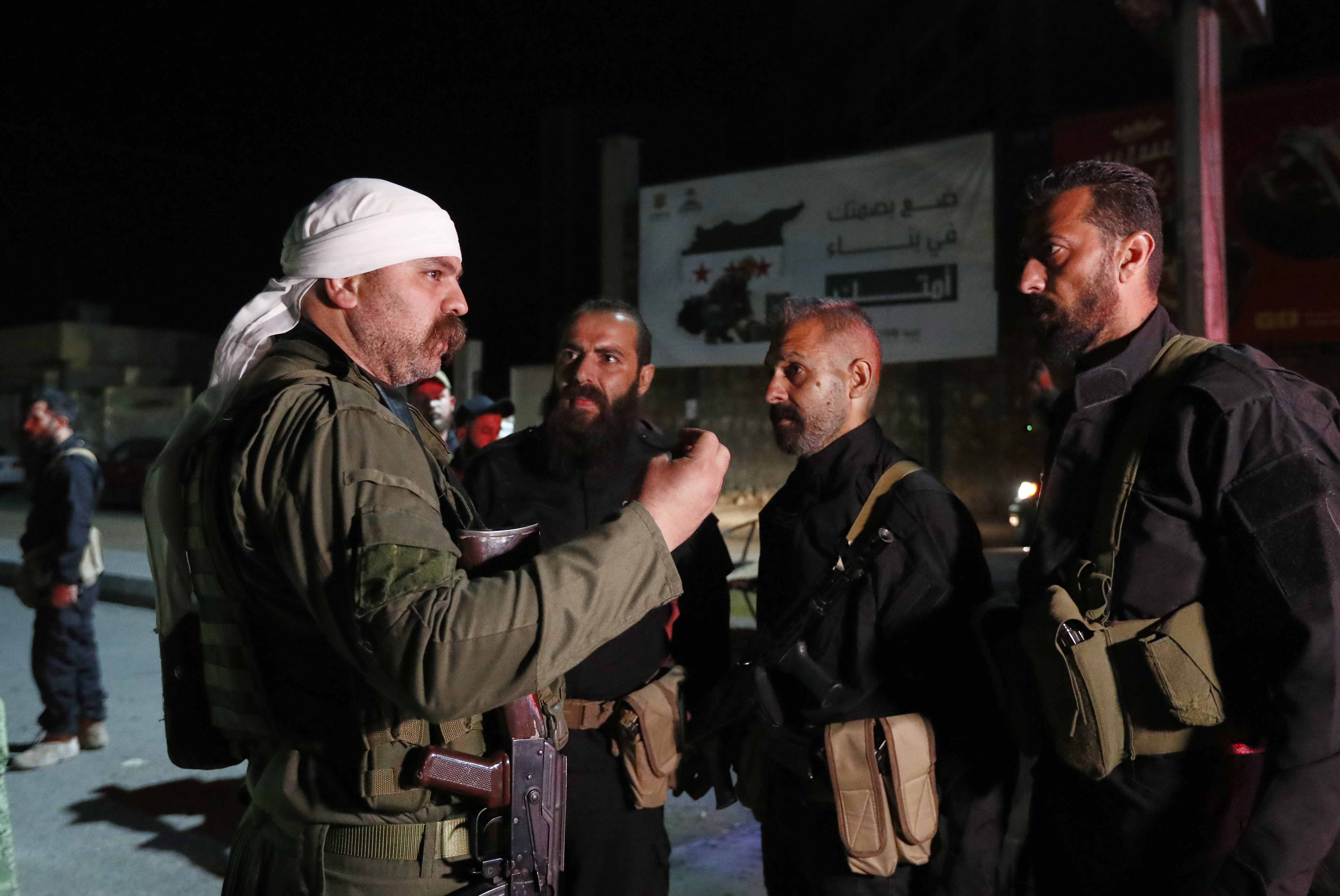 A Druze gunman, left, speaks with Syrian security forces who reached a deal with Druze gunmen to deploy around the southern Damascus suburb of Jaramana that has witnessed fighting earlier this week in Damascus, Syria, early Friday, May 2, 2025. (AP Photo/Omar Sanadiki)