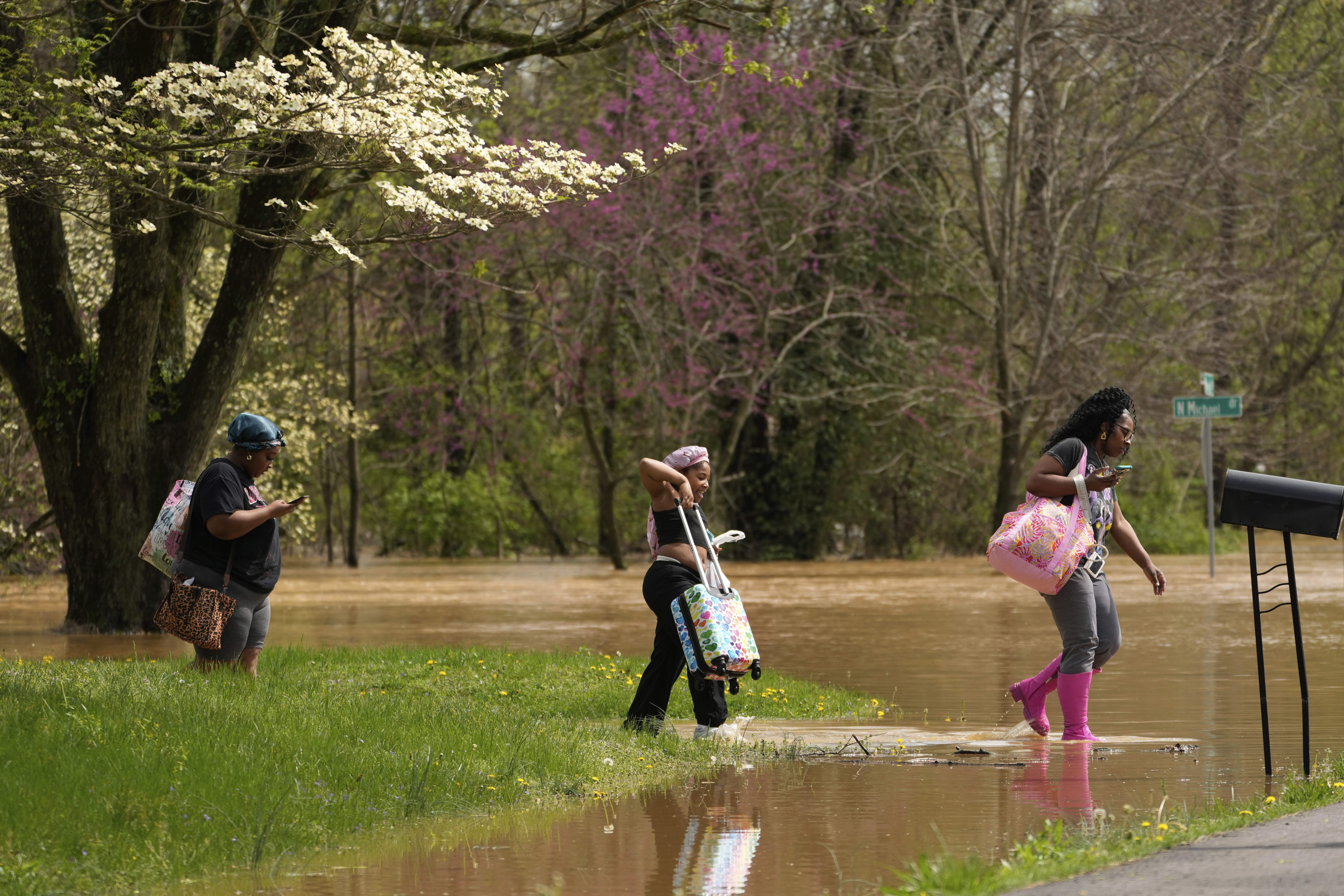 FILE - Marquetta Wheeler, right, with Samaria Williams and Jemaria Shaw, walk through flood waters as they leave their home on Marietta Drive in Hopkinsville, Ky., April 4, 2025. (AP Photo/George Walker IV, File)
