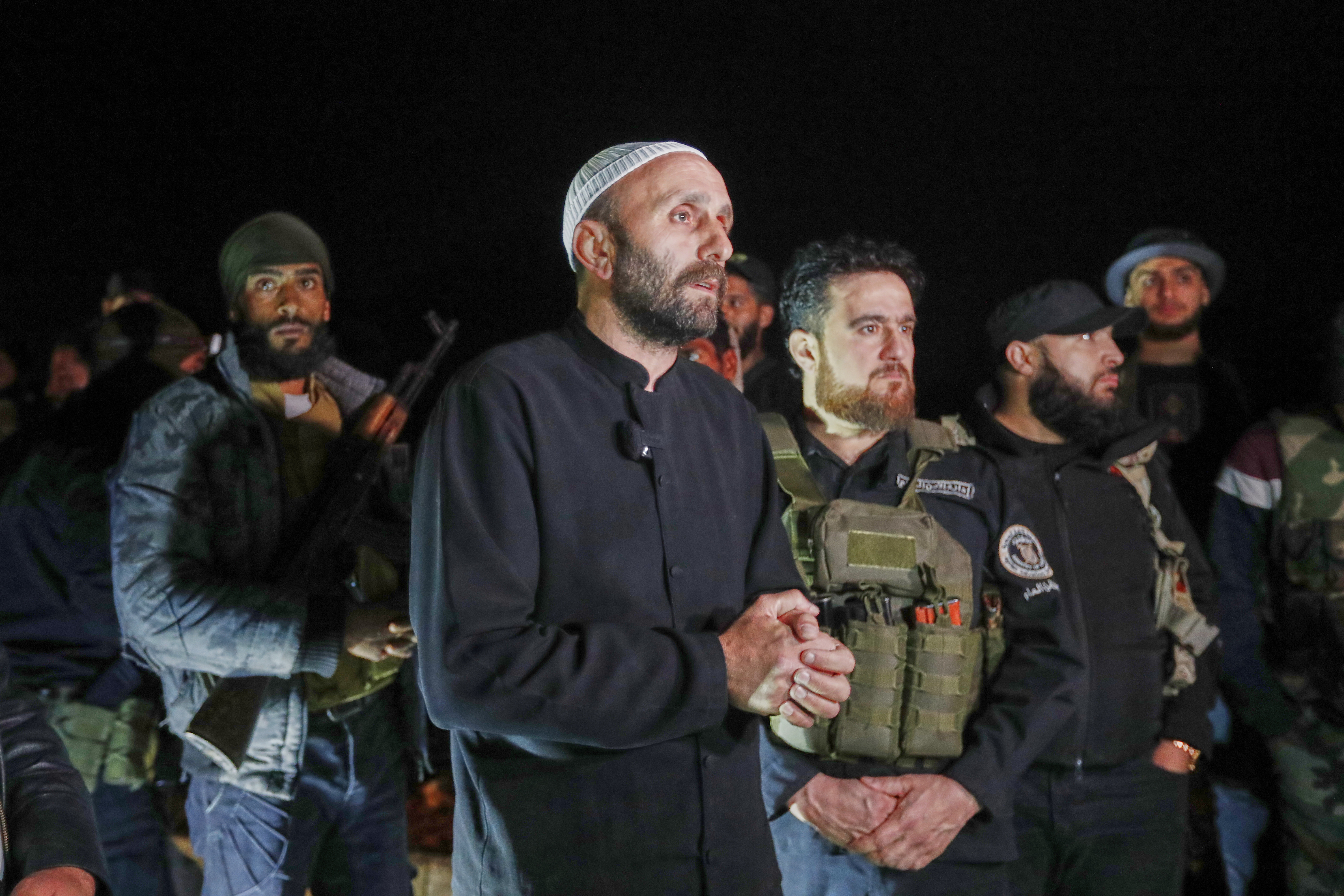 A Druze man, center, stands next to Syrian security forces who reached a deal with Druze gunmen to deploy around the southern Damascus suburb of Jaramana that has witnessed fighting earlier this week in Damascus, Syria, early Friday, May 2, 2025. (AP Photo/Omar Sanadiki)