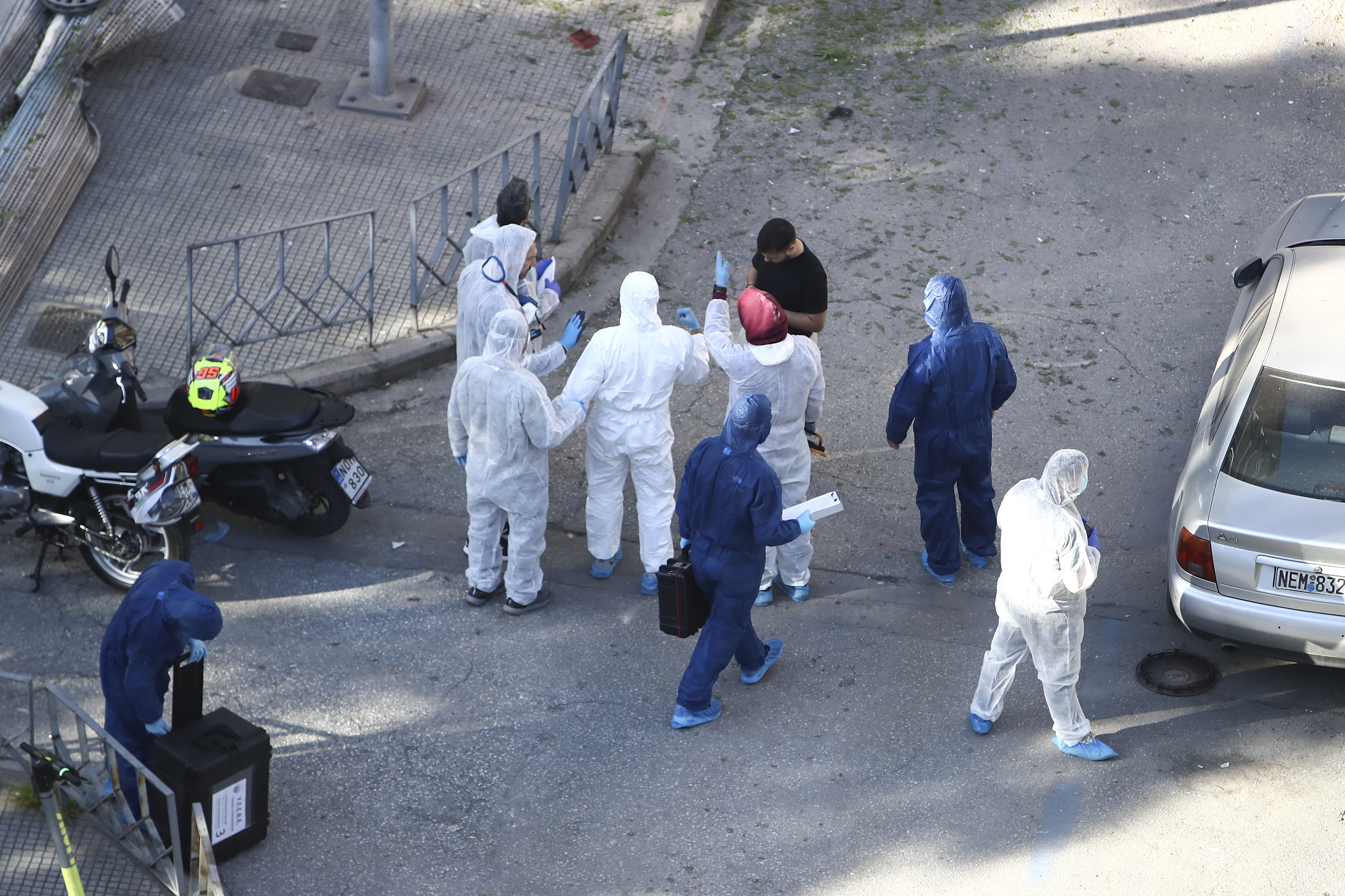Greek police forensic experts search the area where a 38-year-old woman was killed early Saturday when a bomb she was carrying exploded in her hands outside a bank branch, local police said, in Thessaloniki, northern Greece, May 3, 2025. (AP Photo/Giannis Papanikos)