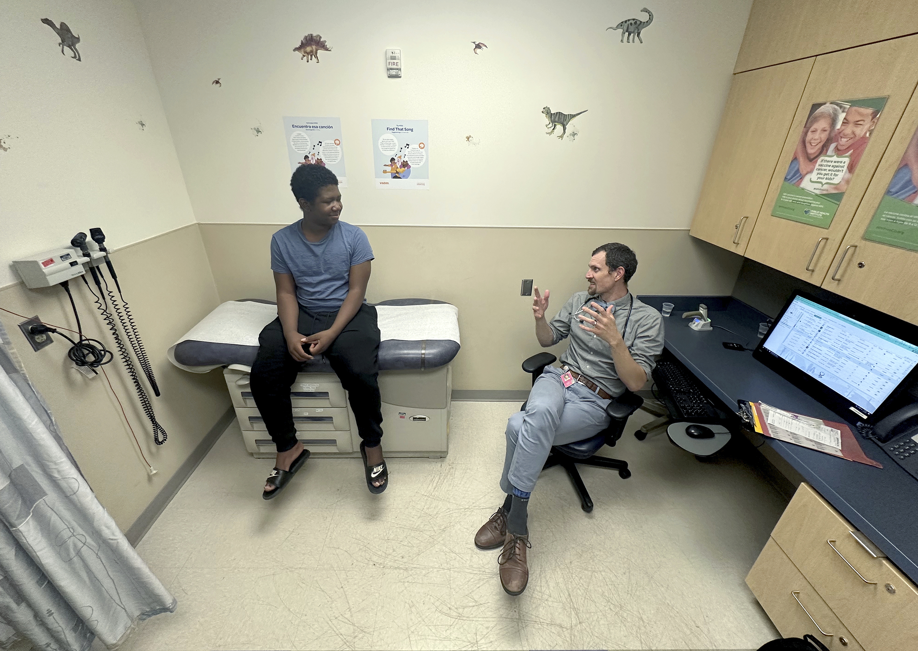 Dr. Joshua Williams, a pediatrician whose federal funding for a vaccine awareness program was cut, talks to 12-year-old patient Tiovian Darden in Denver on Tuesday, March 18, 2025. (AP Photo/Thomas Peipert)