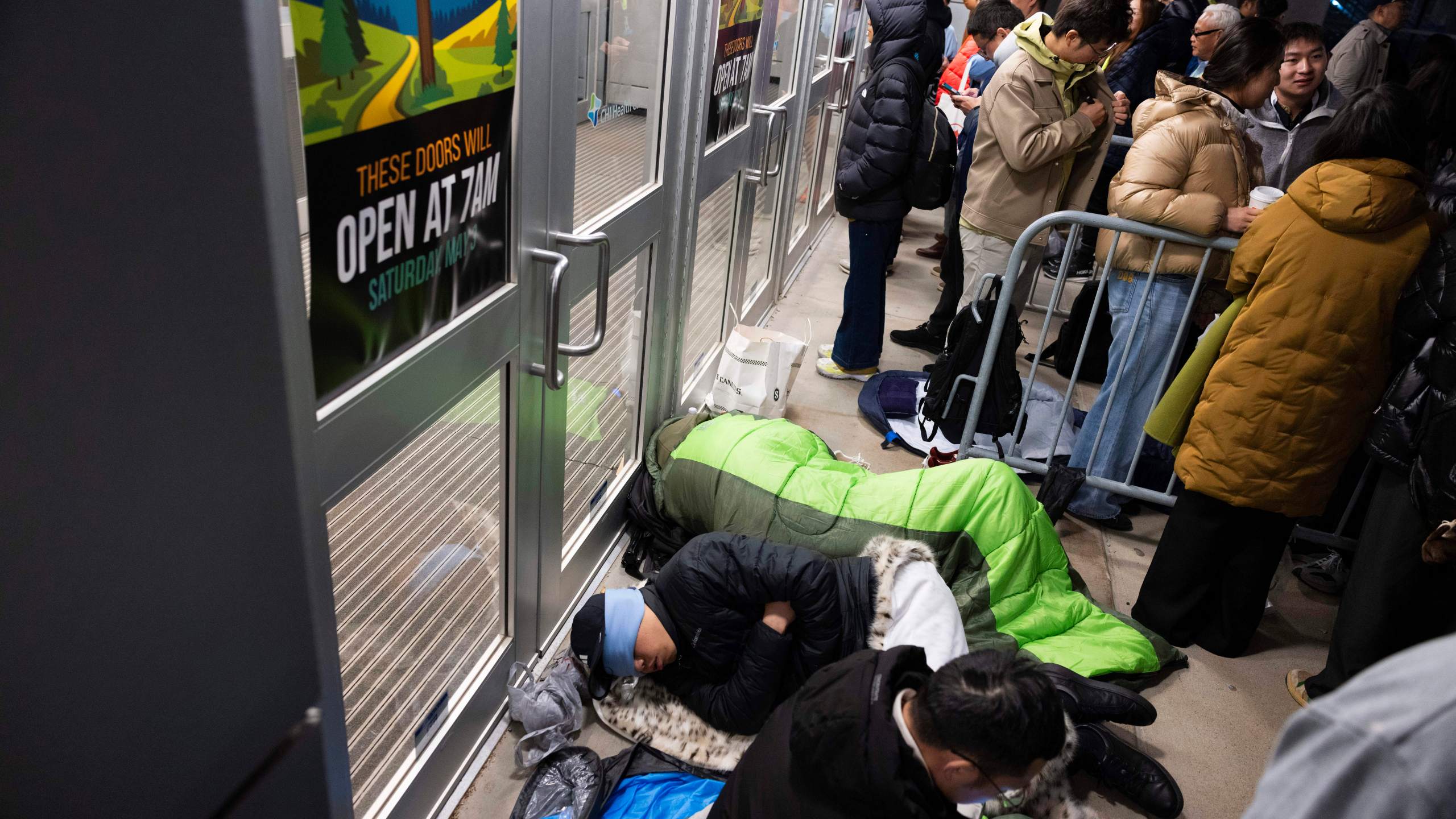 From front, shareholders Haibo Liu, Liyang Jiang and Cheng Guo of China rest in sleeping bags outside CHI Health Center Omaha for the Berkshire Hathaway annual meeting Saturday, May 3, 2025, in Omaha, Neb. The group arrived at 11 p.m. the night before to retain a spot at the front of the line. (AP Photo/Rebecca S. Gratz)