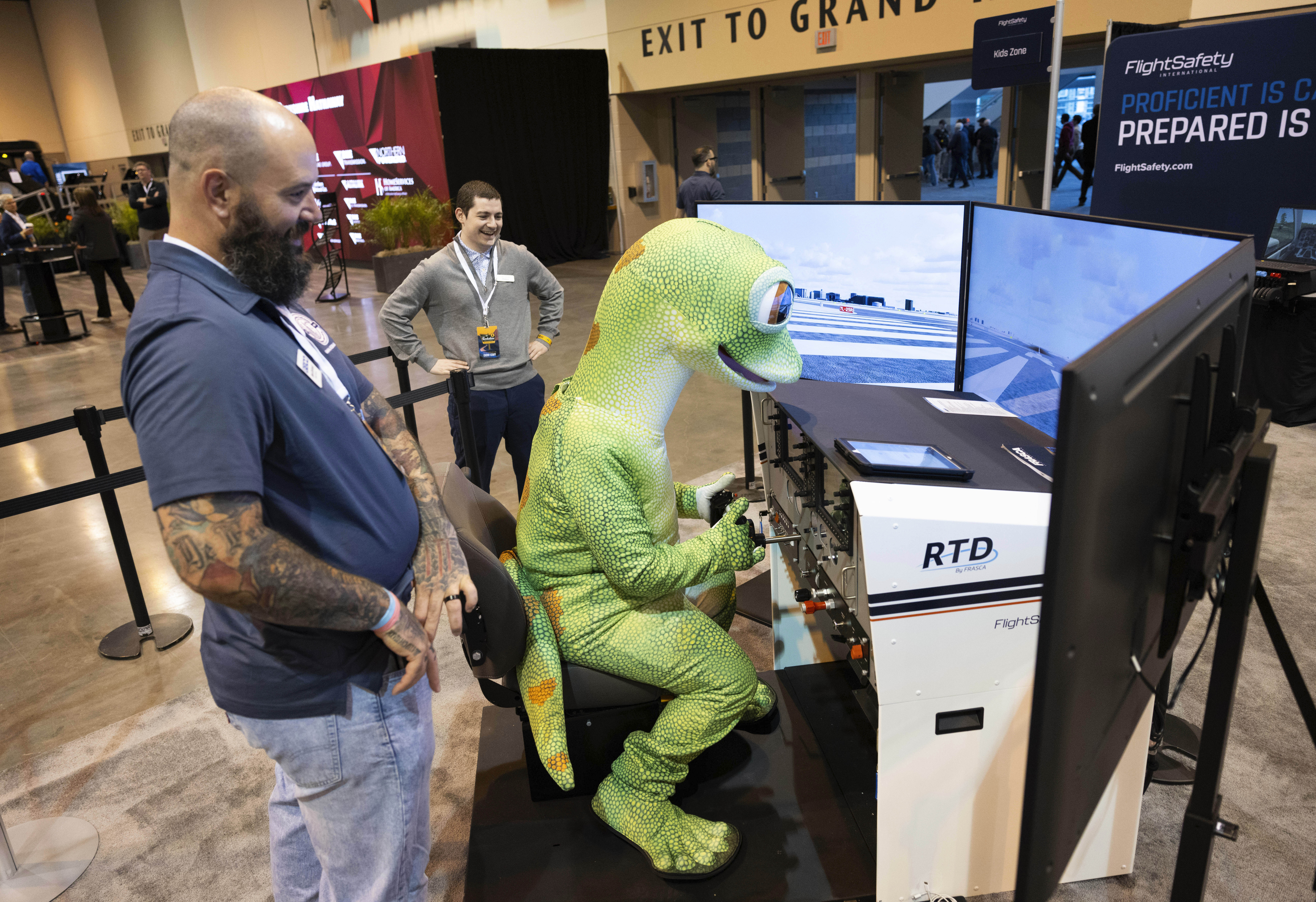 Sean DeFendi of Virginia Beach, left, watches over the GEICO Gecko as he uses the Flight Safety International flight simulator in CHI Health Center Omaha for the Berkshire Hathaway annual meeting Saturday, May 3, 2025, in Omaha, Neb. (AP Photo/Rebecca S. Gratz)