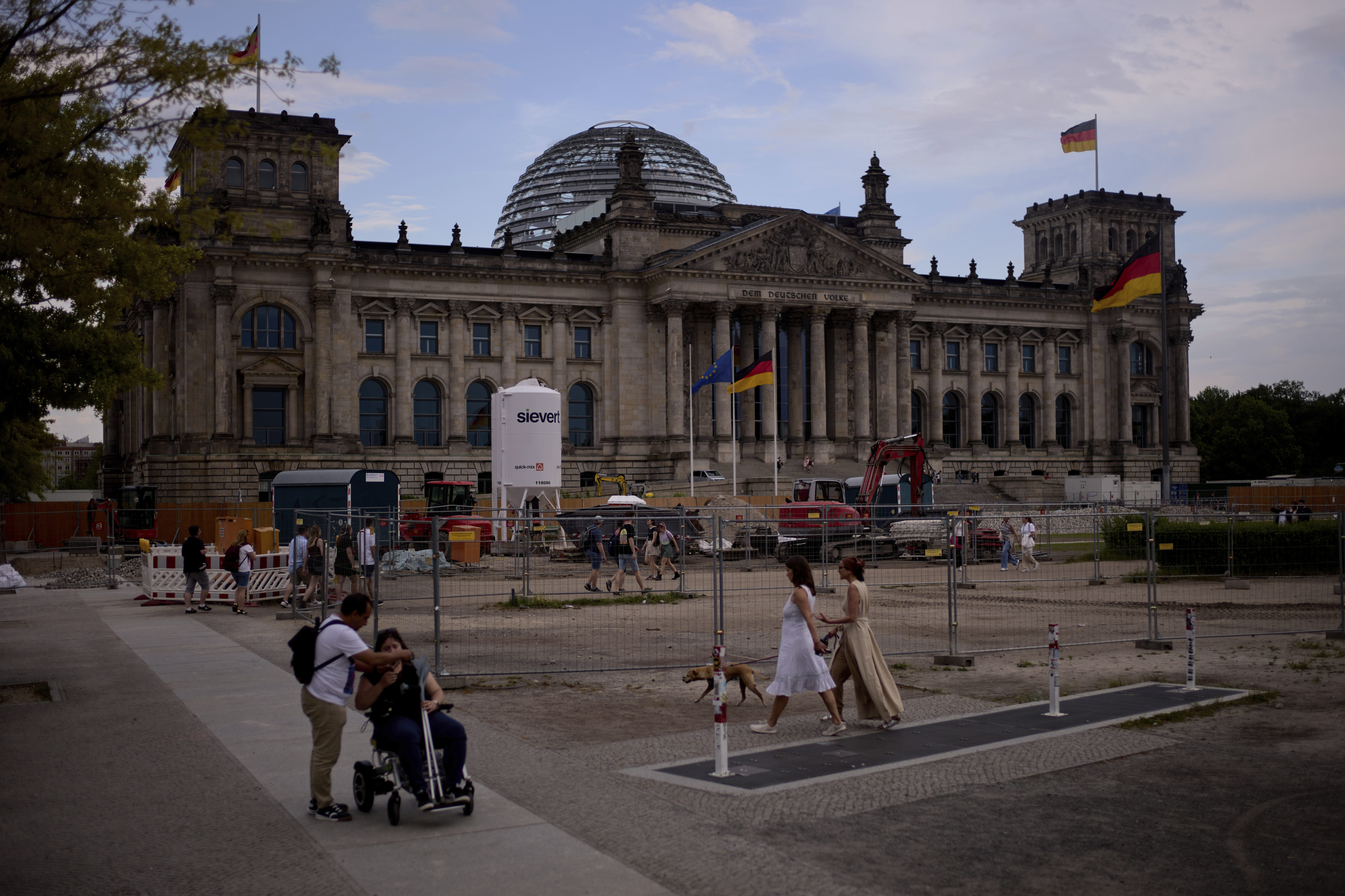 People walk in front of the Reichtag Building, in Berlin, Germany, Friday, May 2, 2025. (AP Photo/Markus Schreiber)