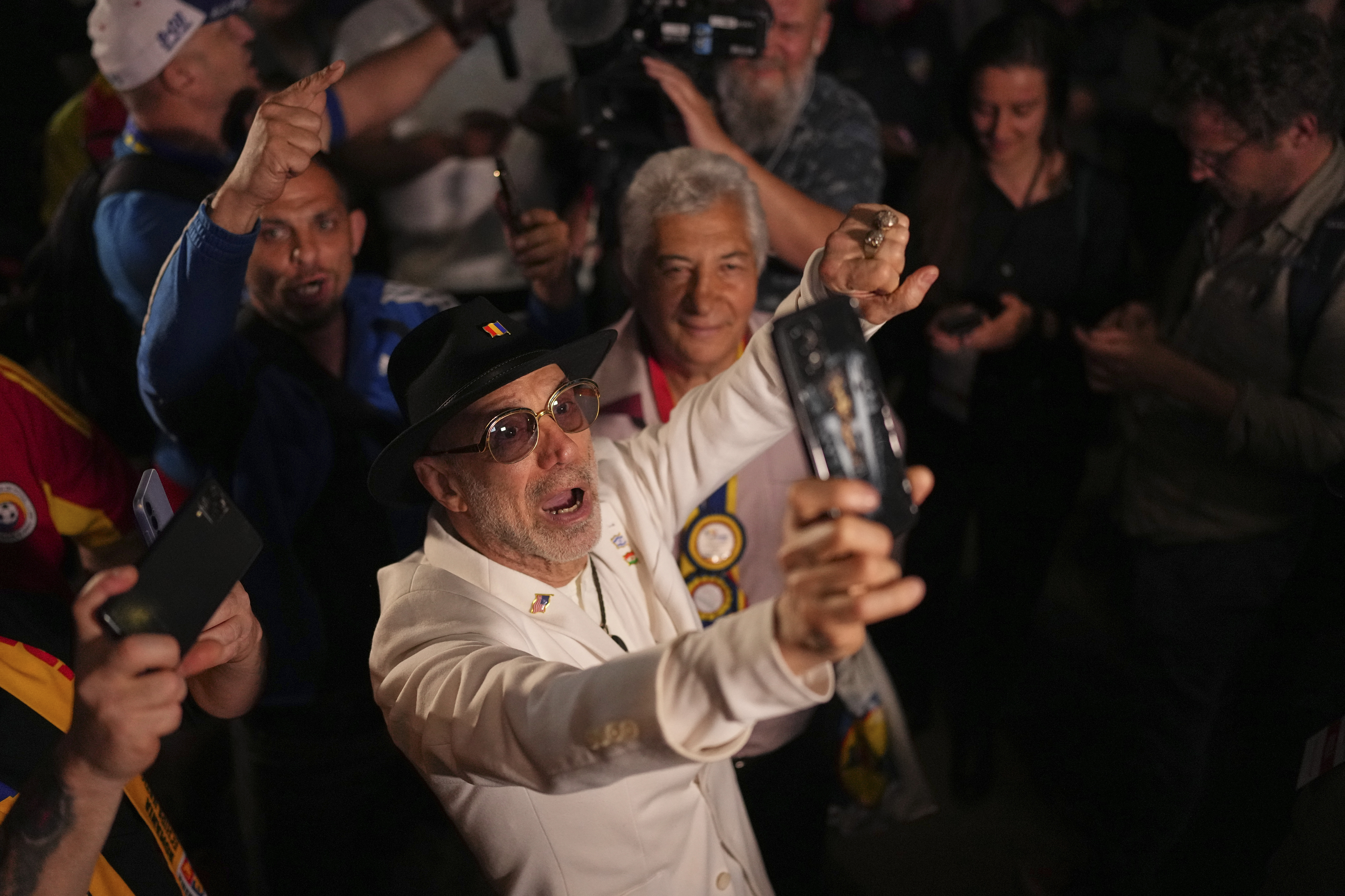 Supporters of Presidential candidate George Simion react to the exit poll results during the first round of the country's presidential election redo in Bucharest, Romania, Sunday, May 4, 2025. (AP Photo/Andreea Alexandru)
