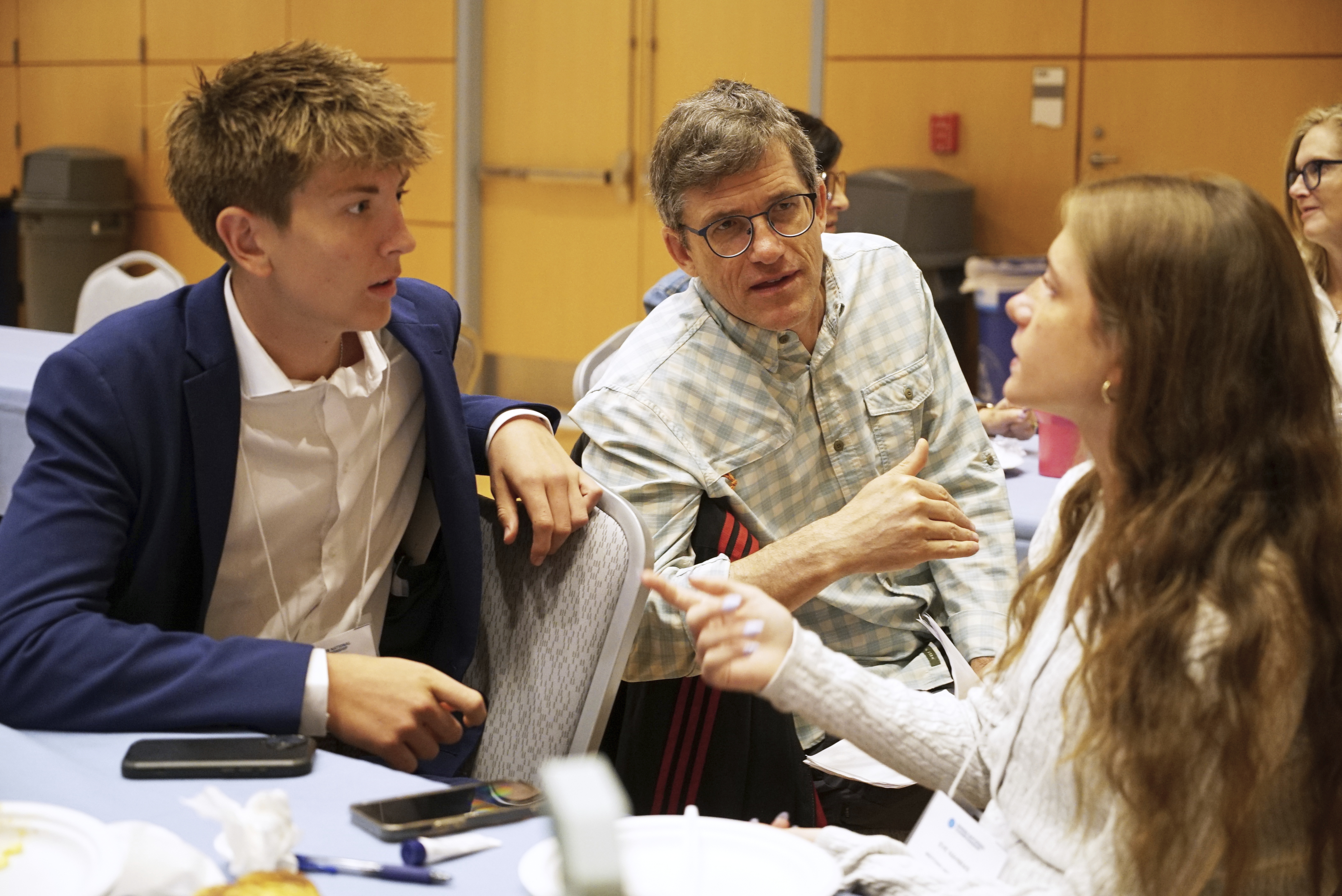 Midtown High School Ethics Bowl teammates Eric Snell, left, and Eve Nahmias speak with coach Eddy Nahmias, Eve's father, in between rounds of the National High School Ethics Bowl in Chapel Hill, N.C., on Sunday, April 13, 2025. (AP Photo/Allen G. Breed)
