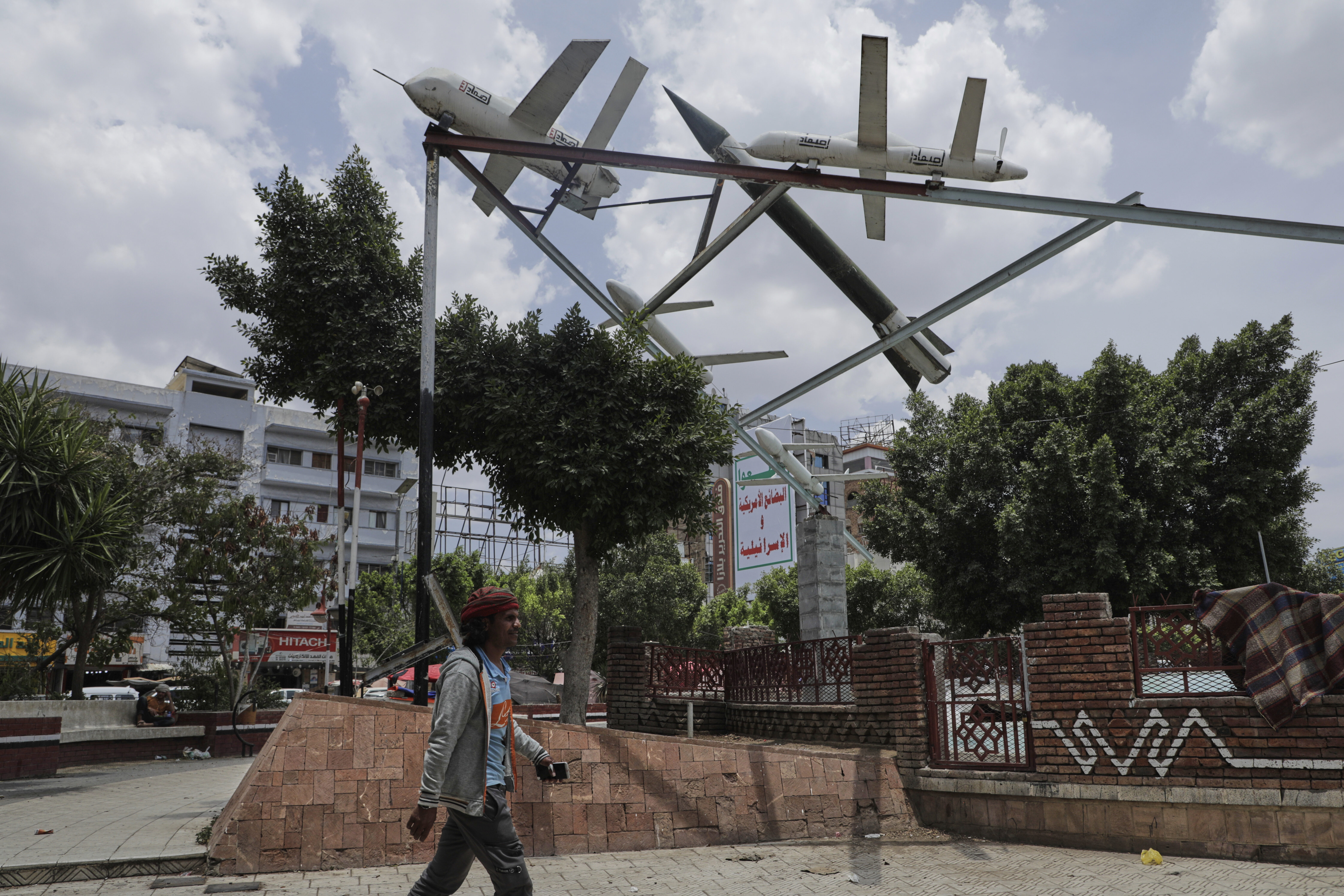 A Yemeni man walks past a monument featuring mock rockets in Sanaa, Yemen, Monday, May 5, 2025. (AP Photo/Osamah Abdulrahman)