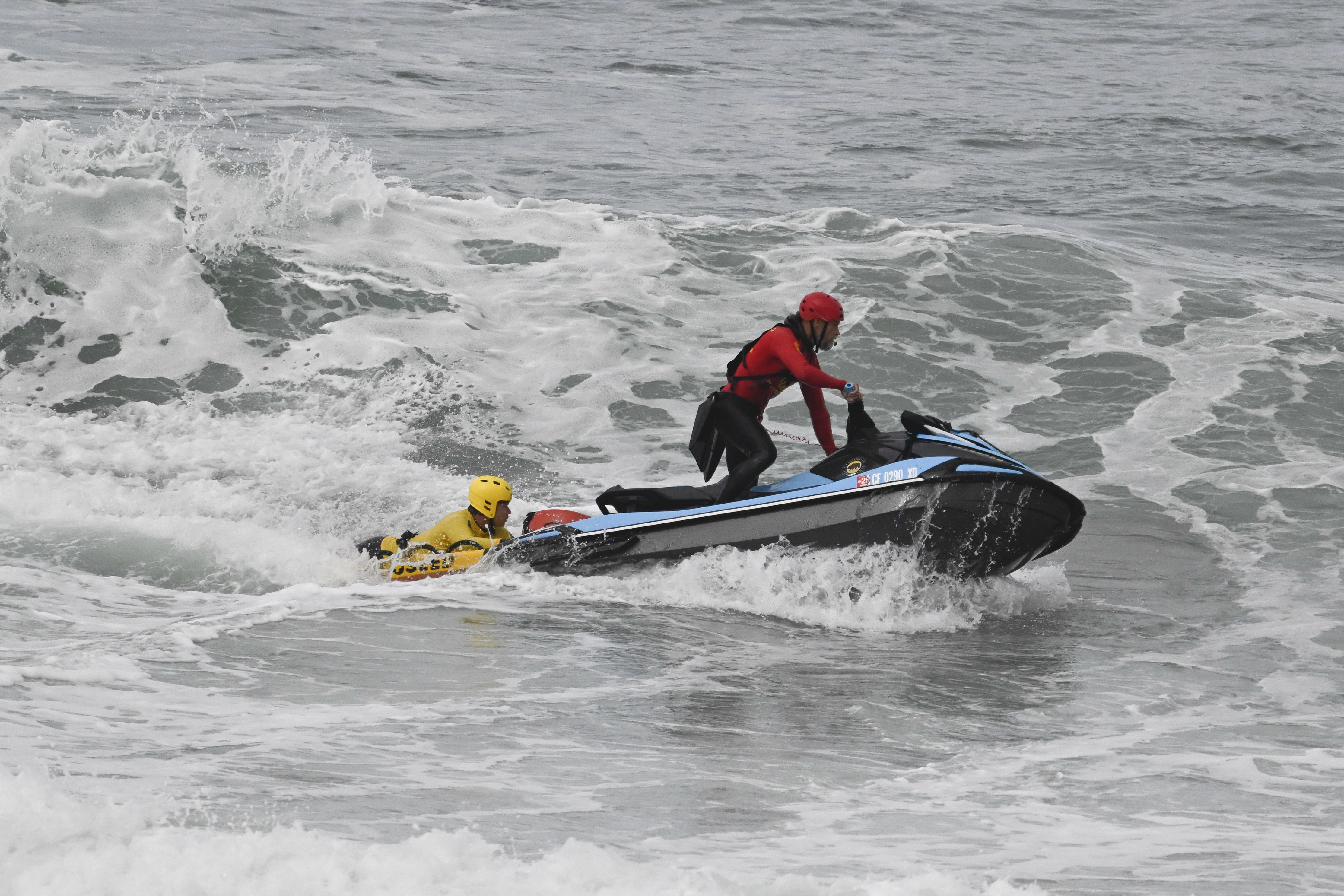 CORRECTS DAY: Lifeguards look for survivors after a boat capsized in the surf Monday, May. 5, 2025, in at Torrey Pines State beach in San Diego, Calif. (AP Photo/Denis Poroy)