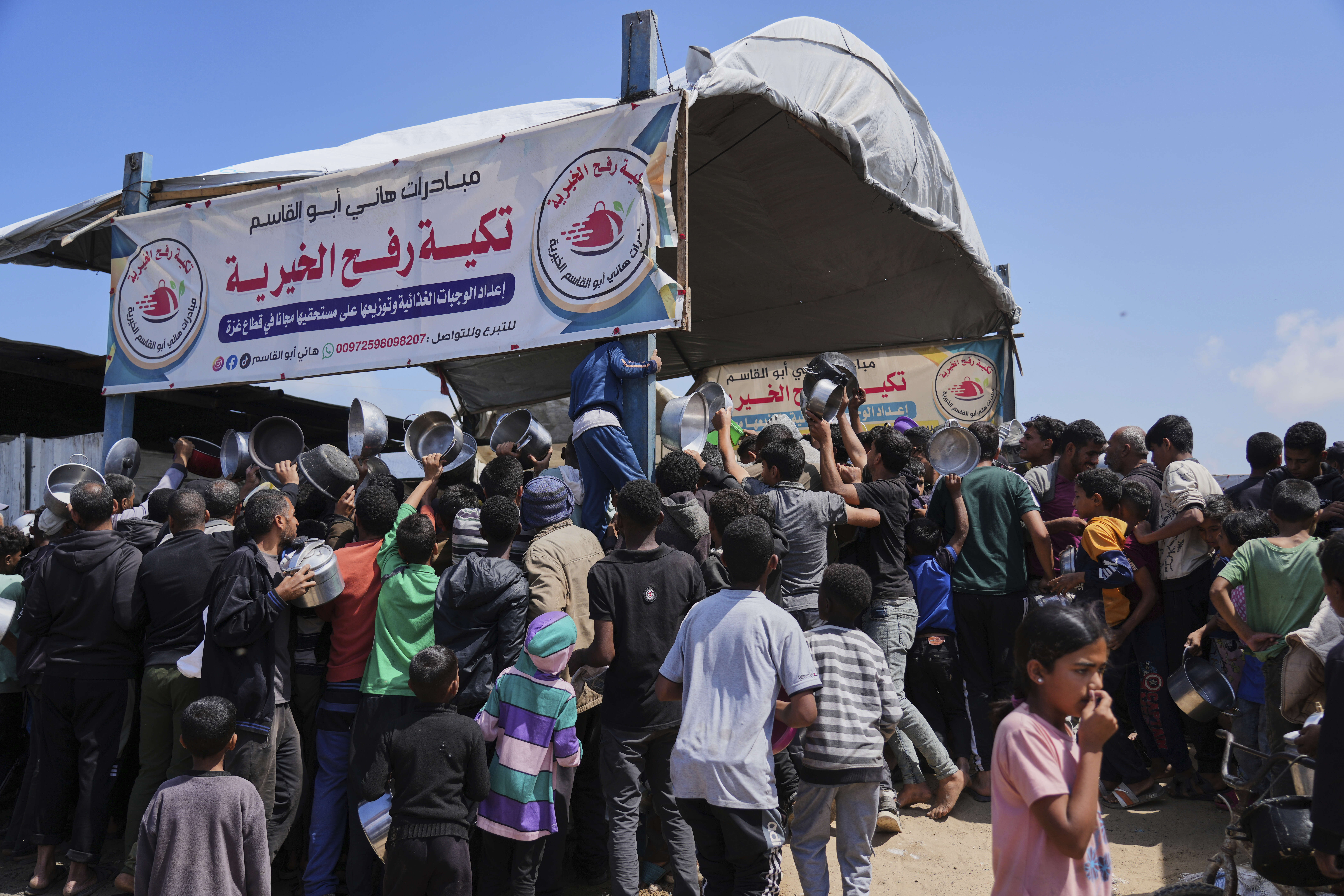 Palestinians struggle to get donated food at a community kitchen in Khan Younis, Gaza Strip, Monday, May 5, 2025. (AP Photo/Abdel Kareem Hana)
