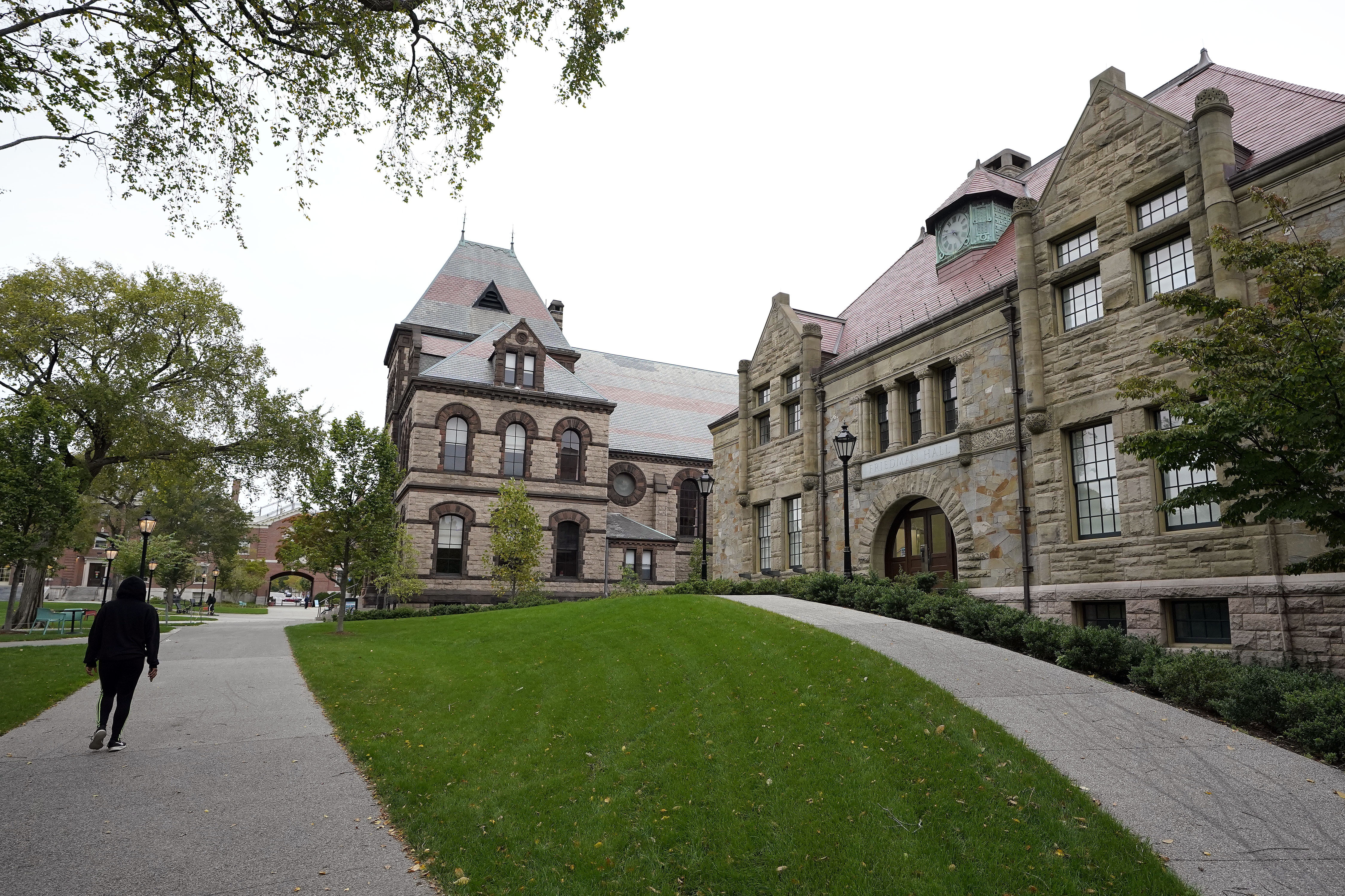 A passer-by walks along a path on the campus of Brown University, in Providence, R.I., Monday, Oct. 12, 2020. (AP Photo/Steven Senne)