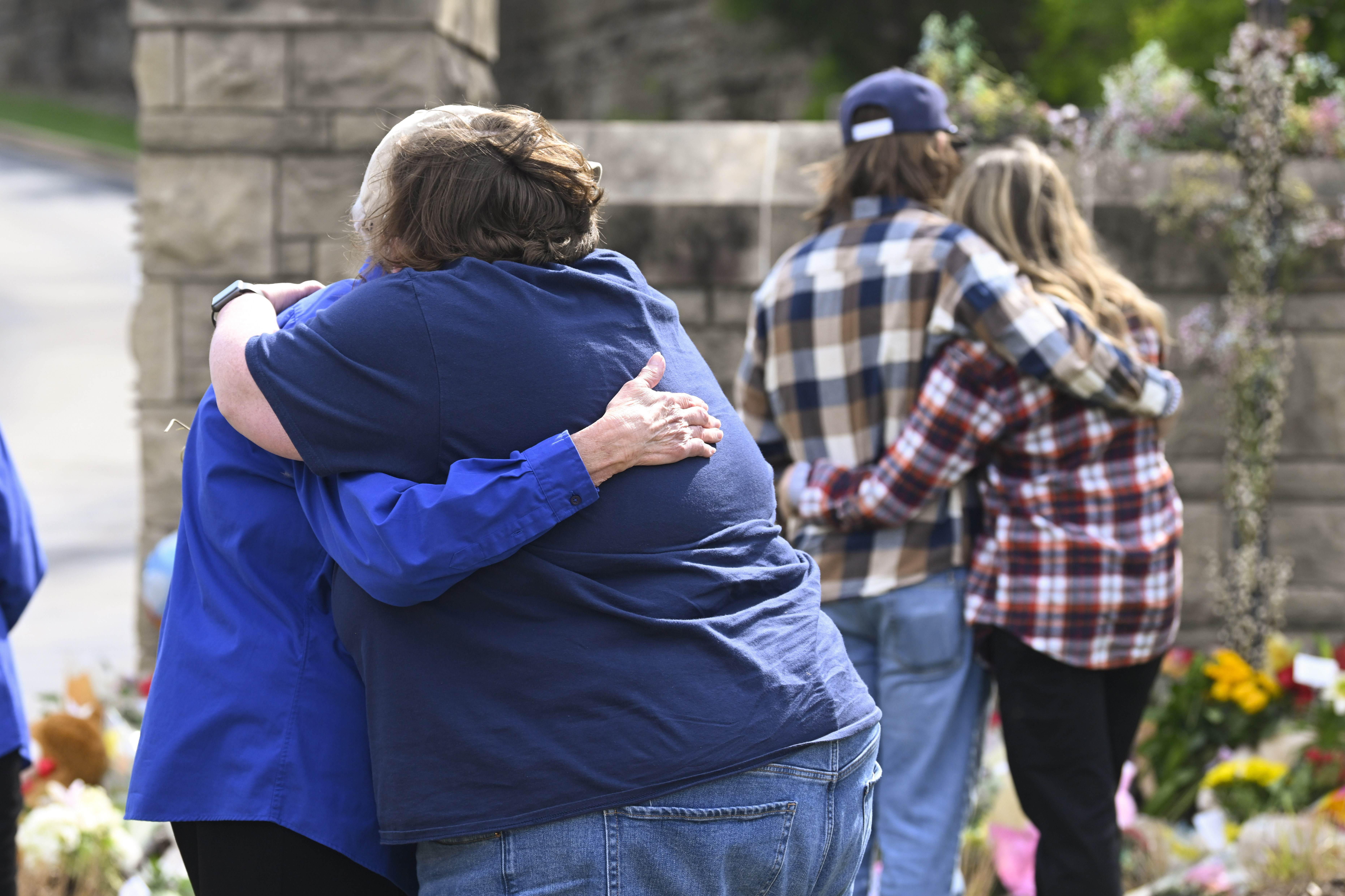 FILE - People console each other at an entry to Covenant School, March 28, 2023, in Nashville, Tenn., which has become a memorial to the victims of Monday's school shooting. (AP Photo/John Amis, file)