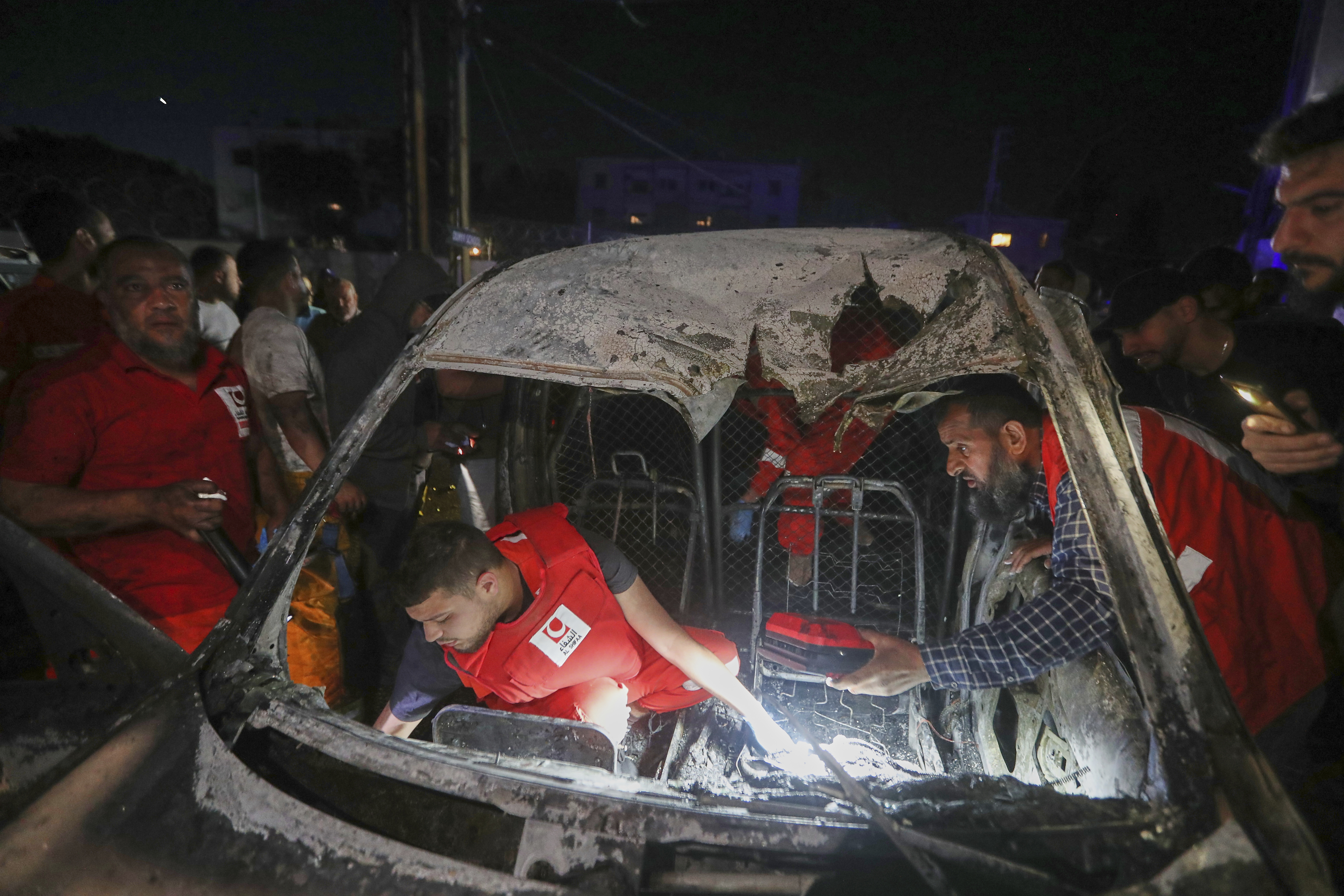 Rescue workers inspect a damaged car after an Israeli strike, in the southern port city of Sidon, Lebanon, early Wednesday, May 7, 2025. (AP Photo/Mohammed Zaatari)