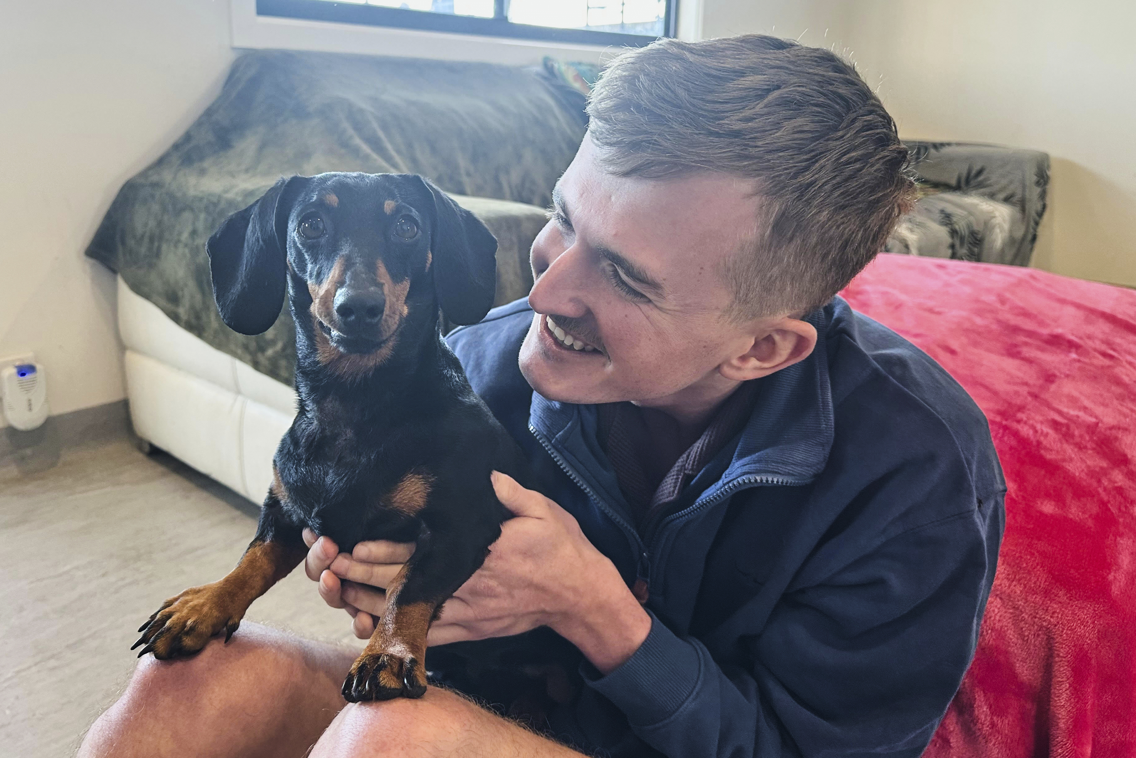 Josh Fishlock holds Valerie, his and partner Georgia Gardner's miniature dachshund after being reunited on Kangaroo Island in South Australia after Valerie was missing for 540 days, Tuesday, May 6, 2025. (Georgia Gardner via AP)