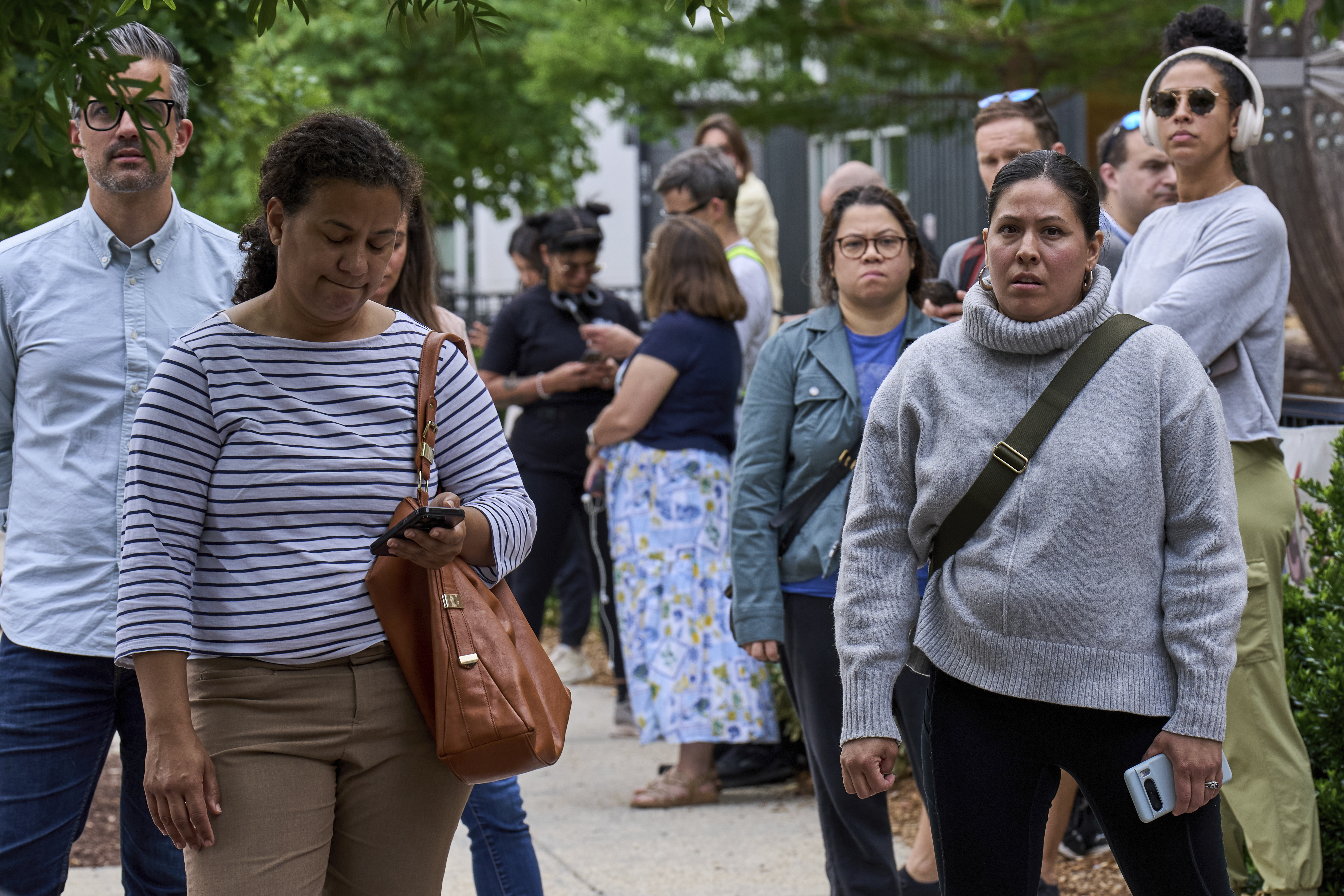 Rio Sigala, right, and other parents of students at Mundo Verde Public Charter School keep a close eye on a Suburban that they thought held an agent of Immigration and Customs Enforcement (ICE) amid fears of impending arrests at schools, Tuesday, May 6, 2025. The vehicle turned out to belong to a television cameraman. "As a Latina, seeing how many parents are out here in solidarity makes you feel less alone," Sigala said. "You walk around kind of scared and to see everyone come out, it feels hopeful." (AP Photo/Jacquelyn Martin)