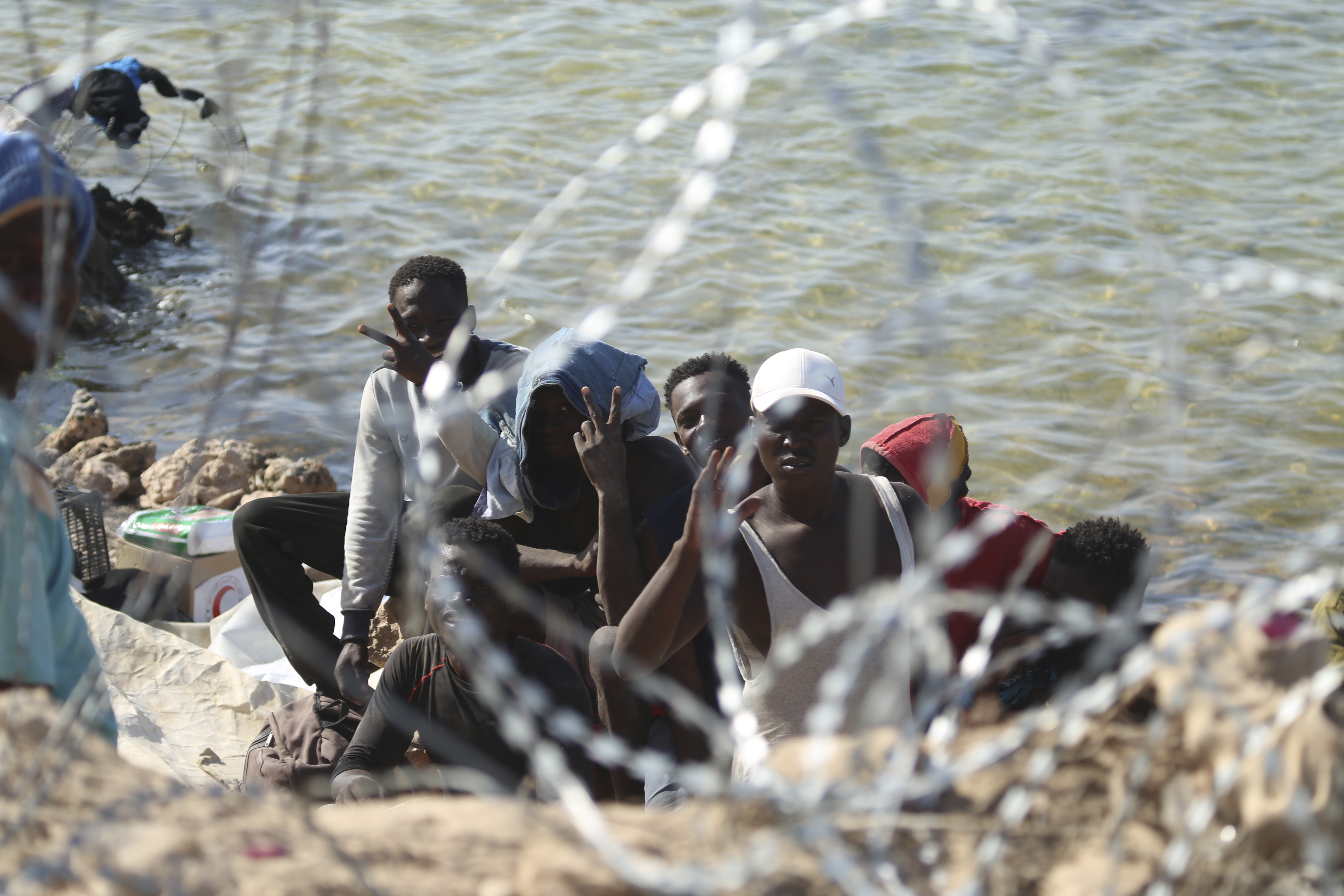 FILE - Migrants gather in an area near the Libyan-Tunisia border, as Libyan security forces and Libyan Red Cross workers distribute food aid to them on Sunday, July 23, 2023. (AP Photo/Yousef Murad, file)