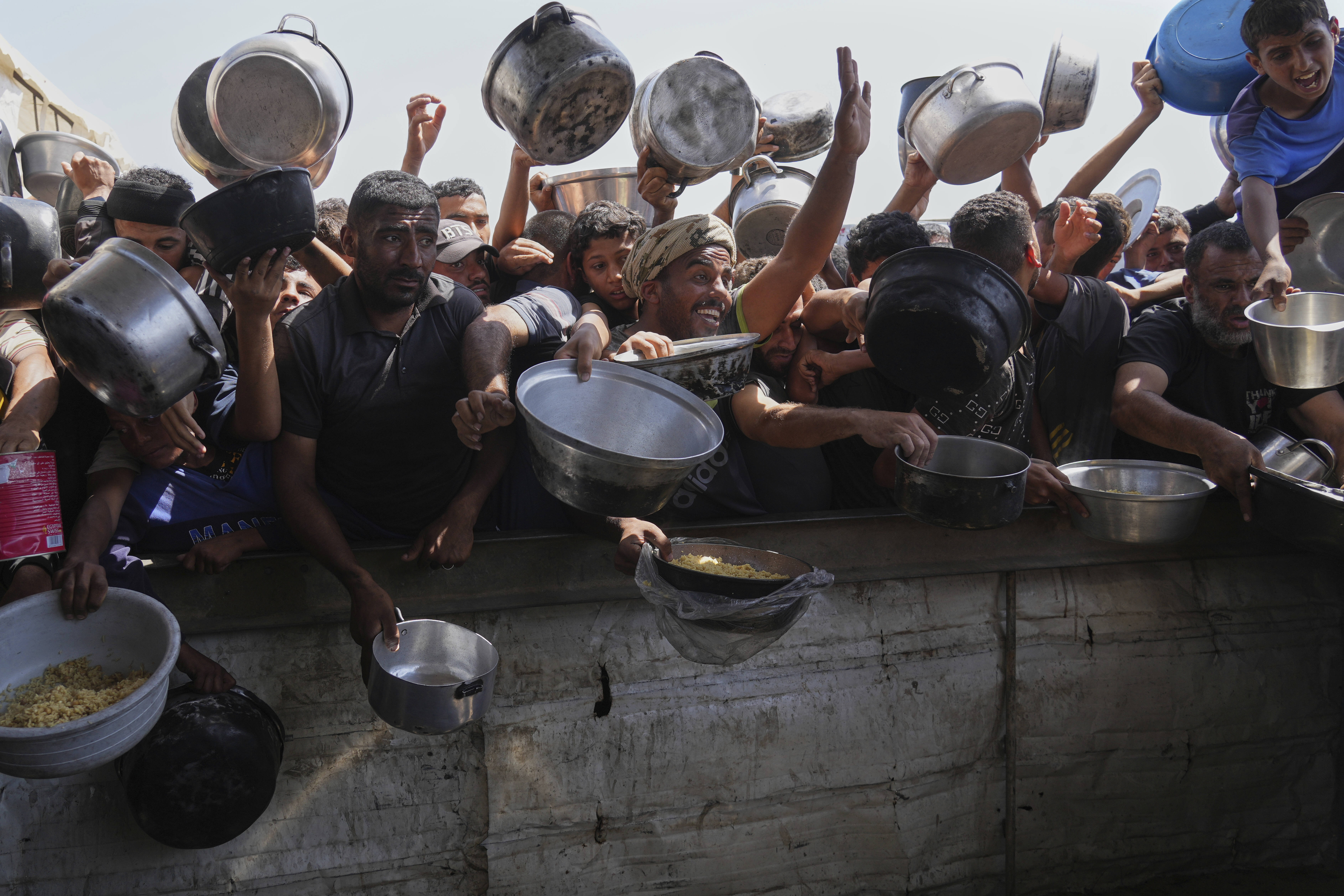 Palestinians struggle to obtain donated food at a community kitchen in Khan Younis, in the southern Gaza Strip, Friday, May 9, 2025. (AP Photo/Abdel Kareem Hana)